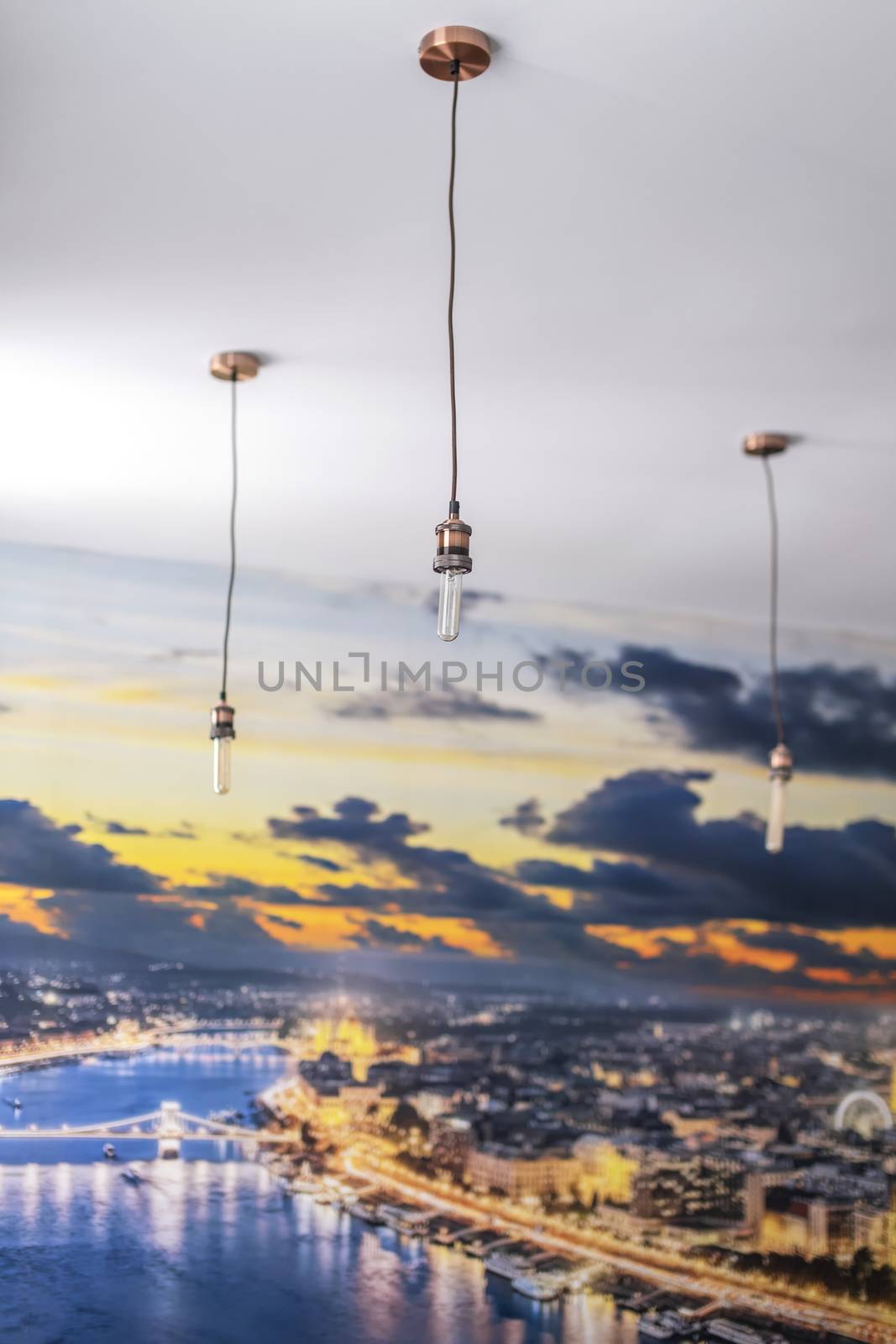 Set of three rose gold light fixtures in front of a white wall and a floor to ceiling poster cityscape wallpaper background in a bright apartment.