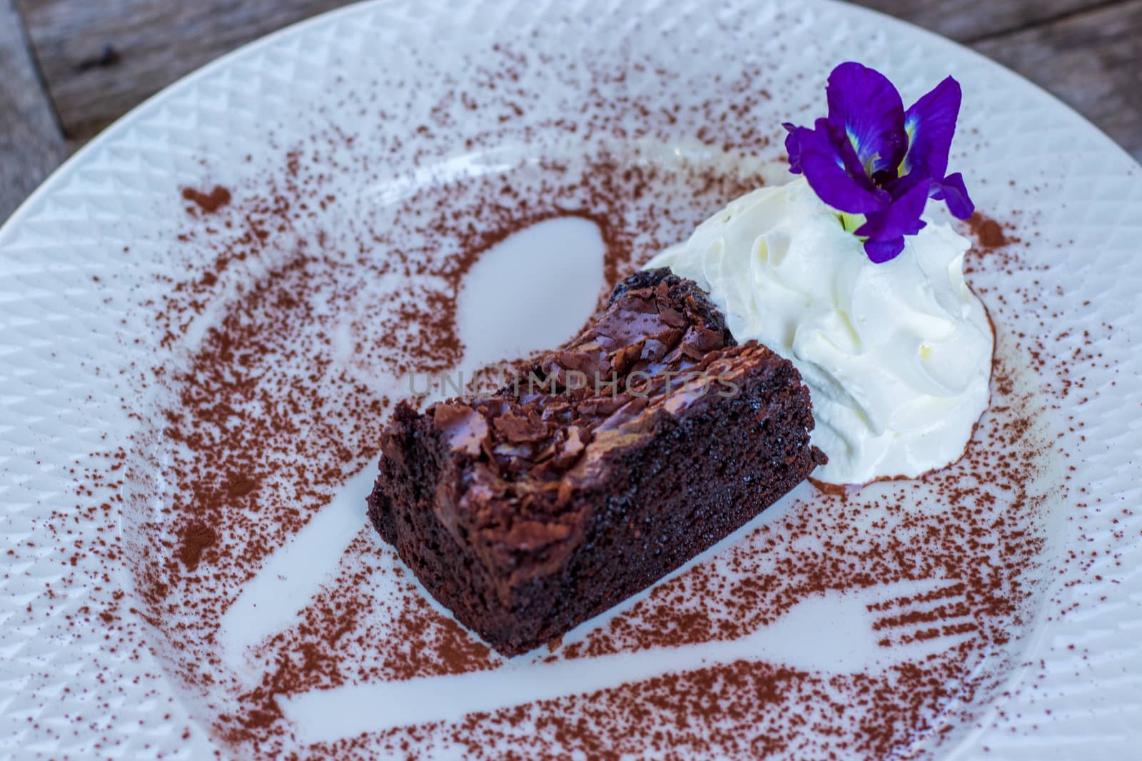 ิbrownie cake with chocolate and flowers on white dish