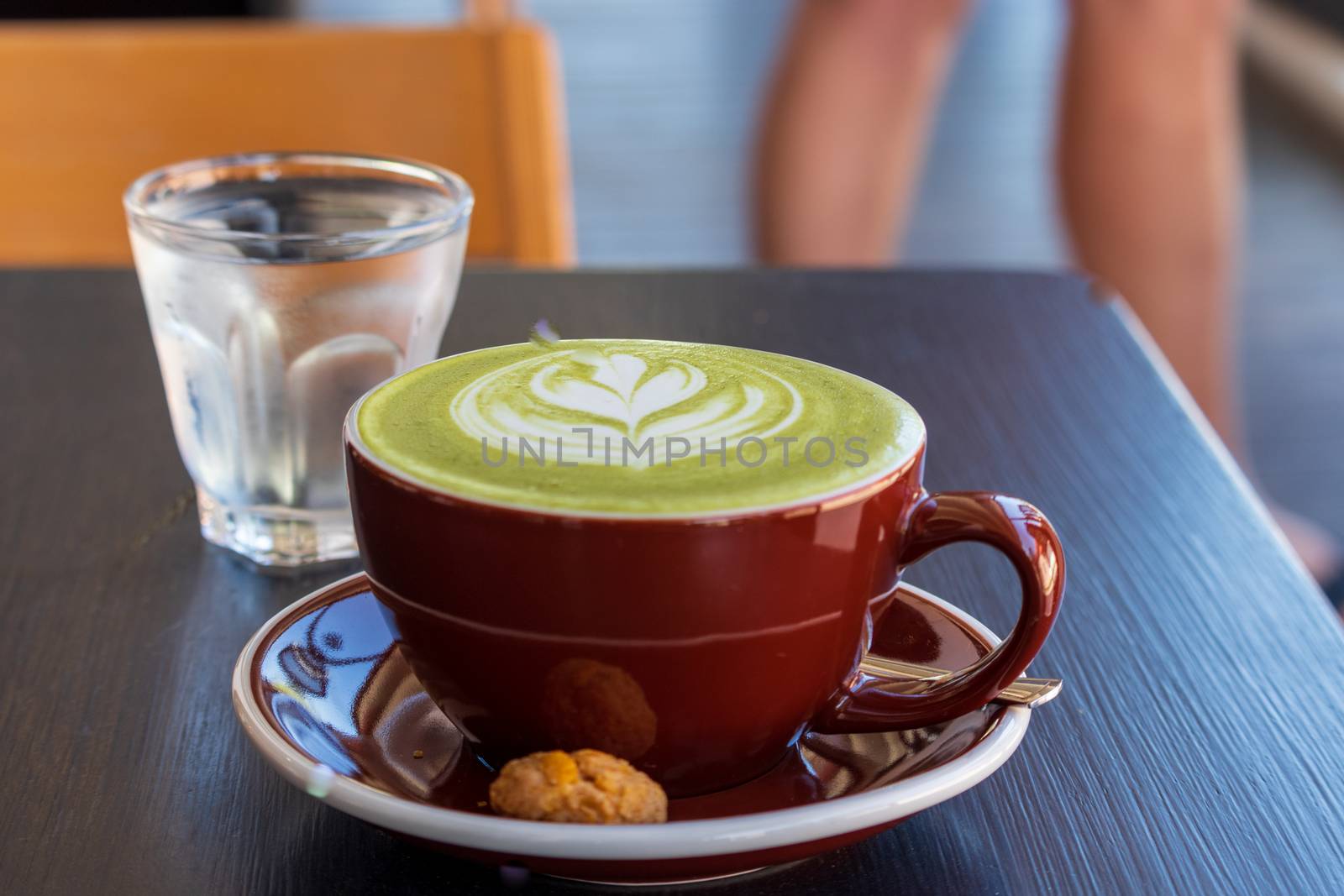 cup of hot matcha green tea latte on wooden table by Khankeawsanan