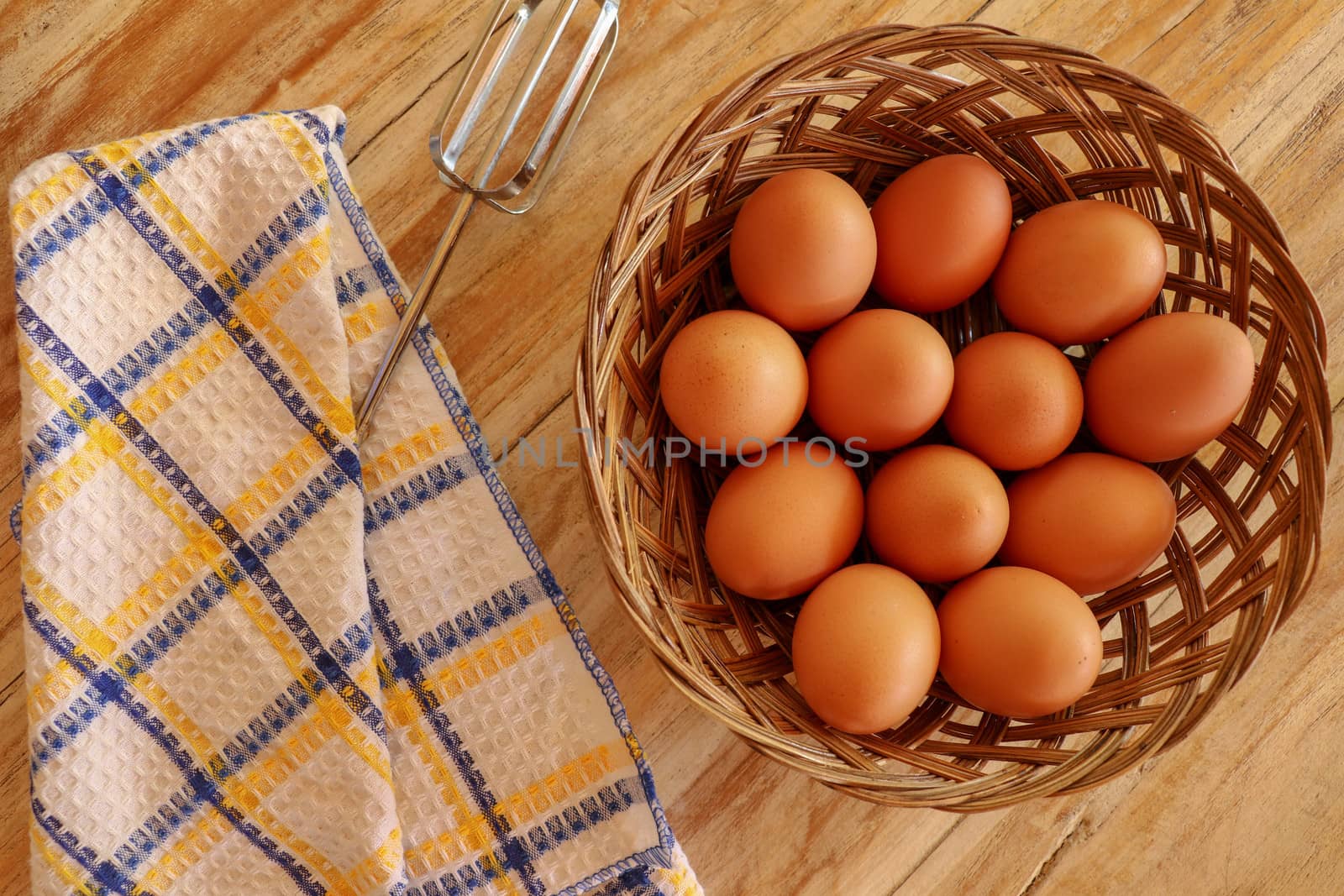 Top view of brown eggs in a wicker basket. Eggs in a wooden basket on a wooden table.