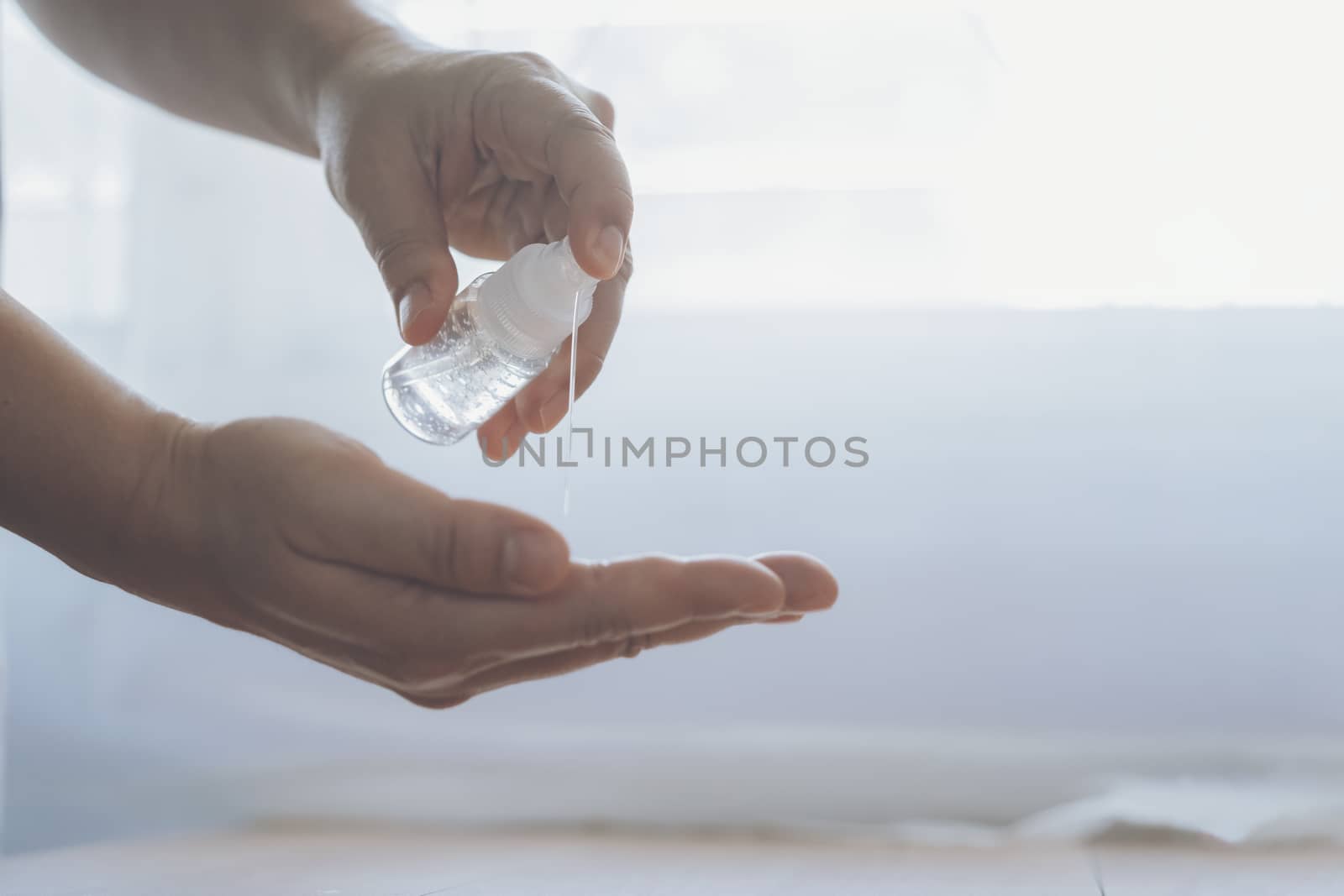 COVID-19, Close up man using bottle of antibacterial wash hand sanitizer gel dispenser, against Novel coronavirus (2019-nCoV) at home.  Home isolation and Healthcare concept.