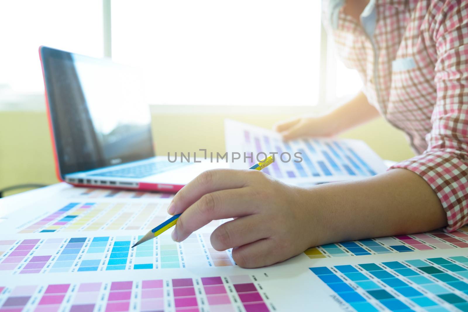 Woman working with color samples for selection. Graphic designer at work. Color swatch samples.
