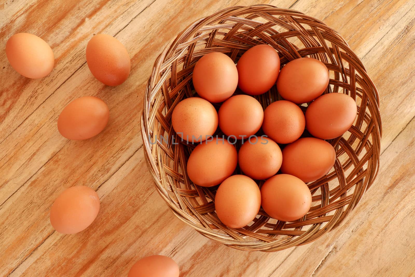 Top view of brown eggs in a wicker basket. Eggs in a wooden basket on a wooden table.