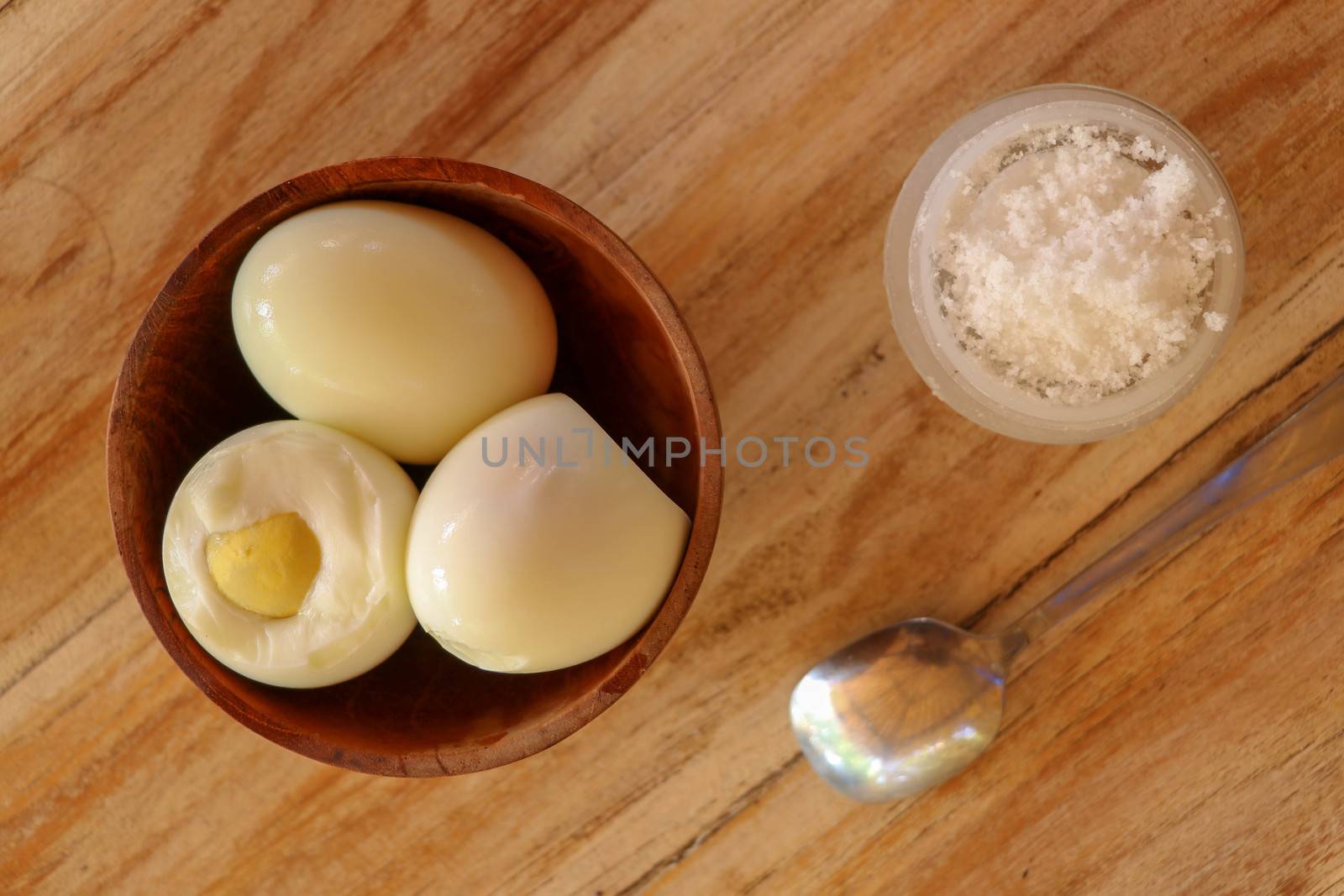 Boiled eggs with salt and herbs on a wooden table. Top view.