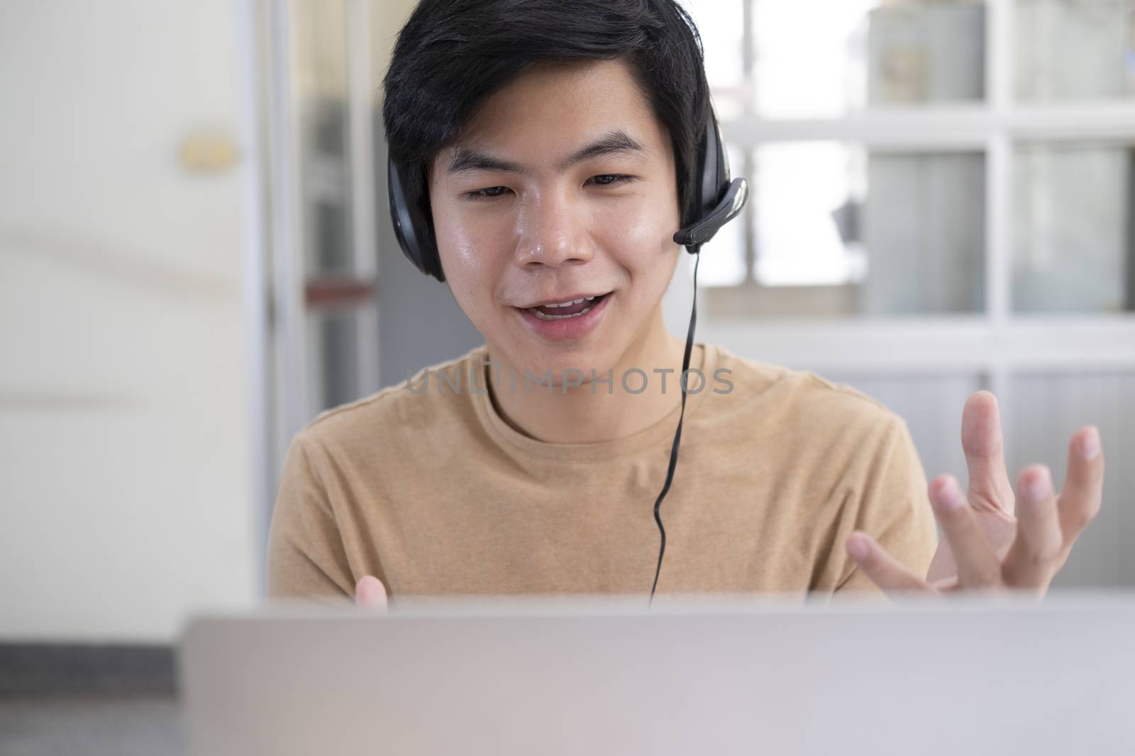 Online meeting and working at home or office. Happy young man speaking looking and using laptop for video conference. 