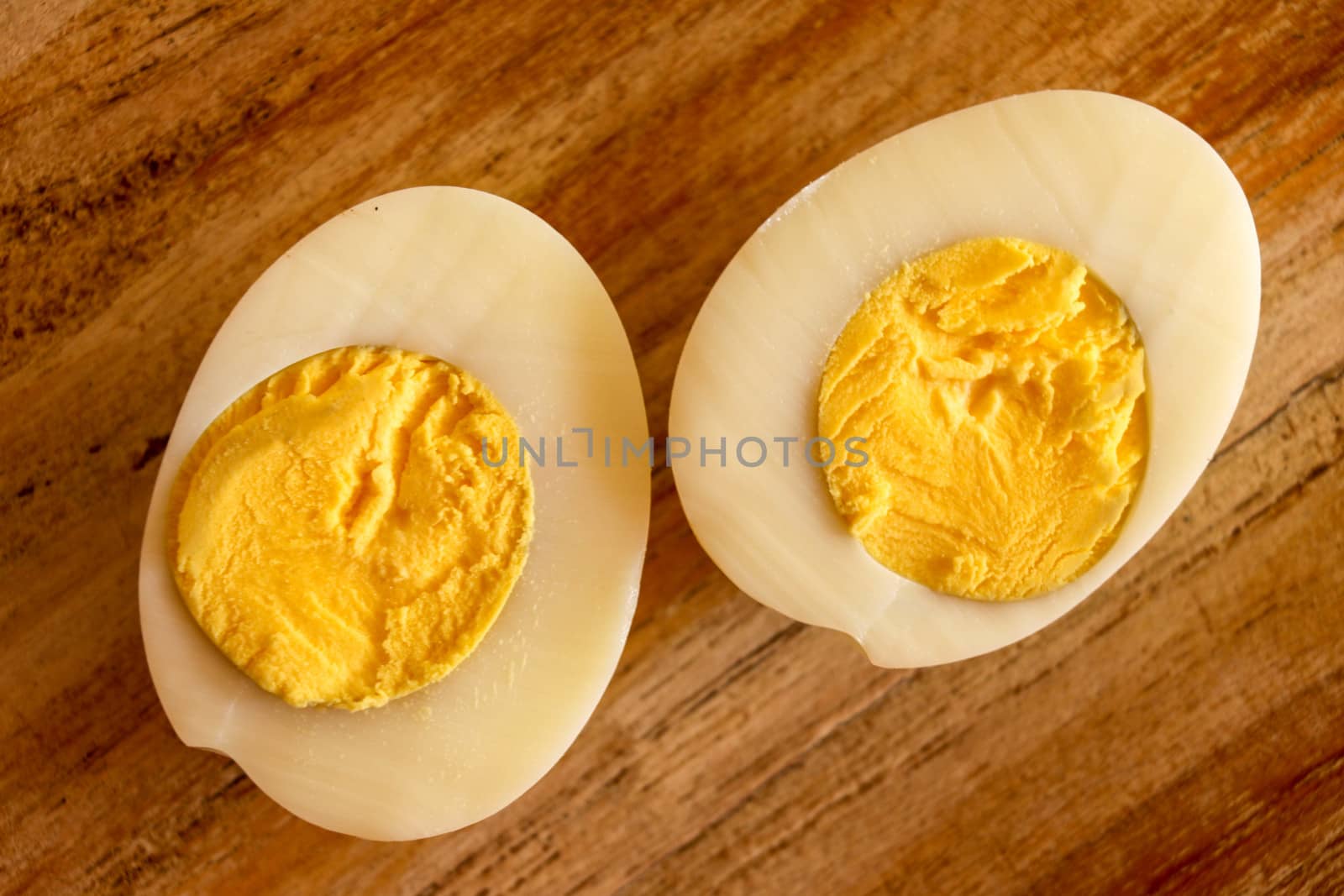 Hard boiled eggs, sliced in halves on wooden background.