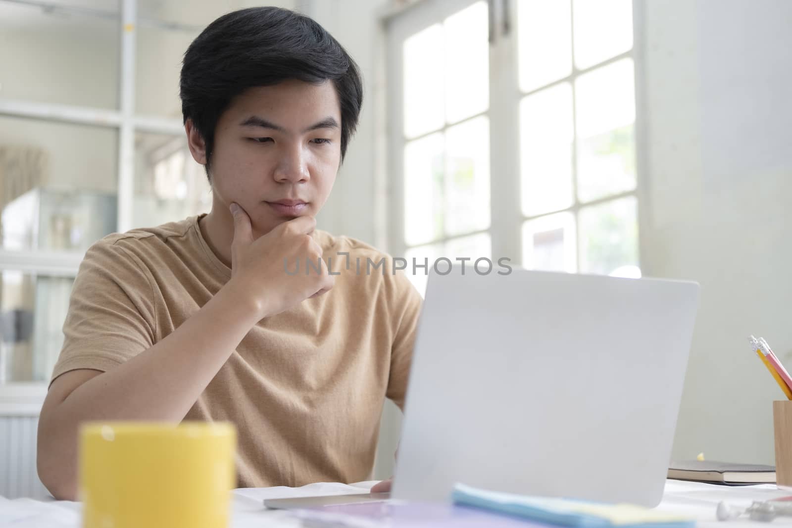 Young man using laptop for working from home office by ijeab