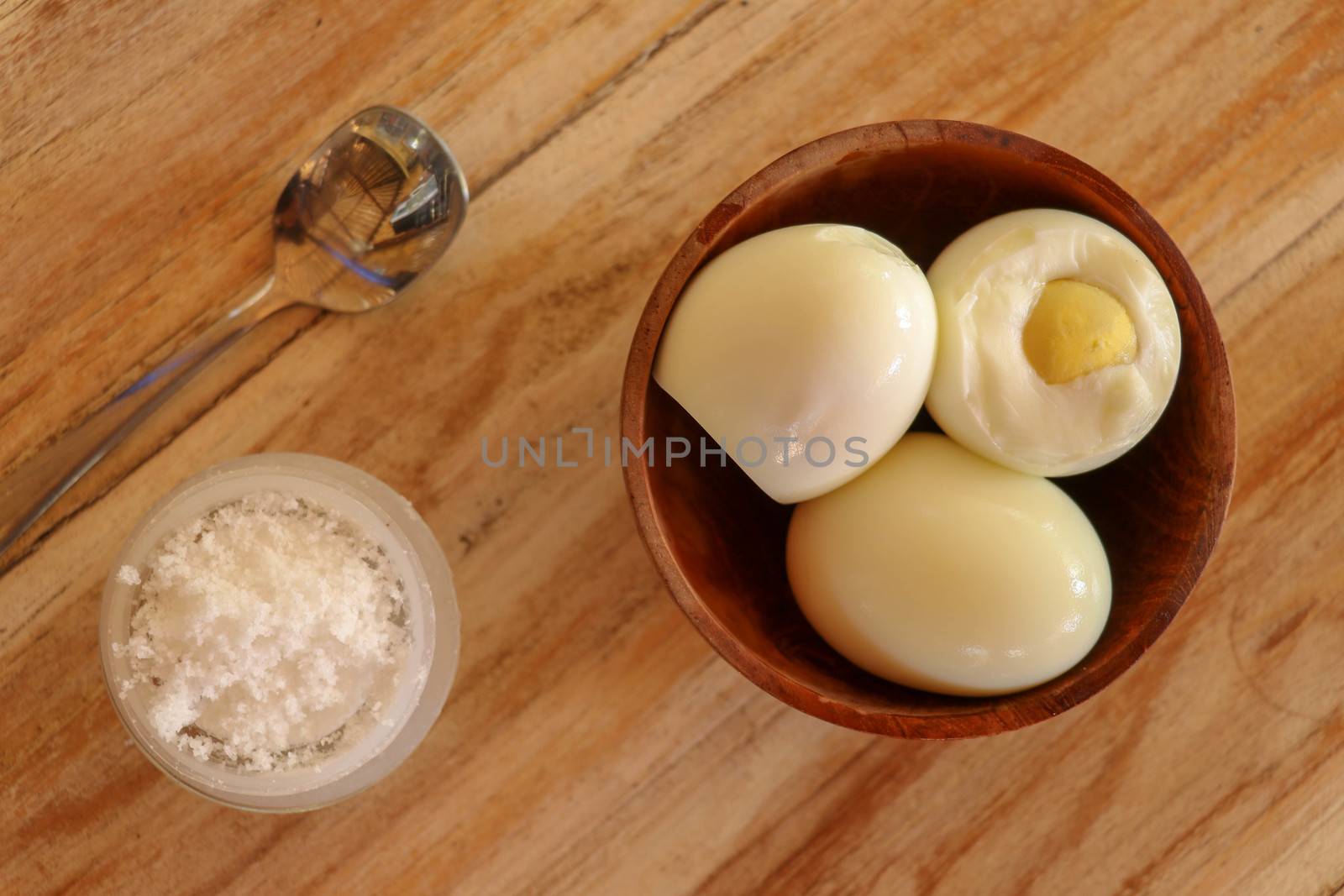 Boiled eggs with salt and herbs on a wooden table. Top view.
