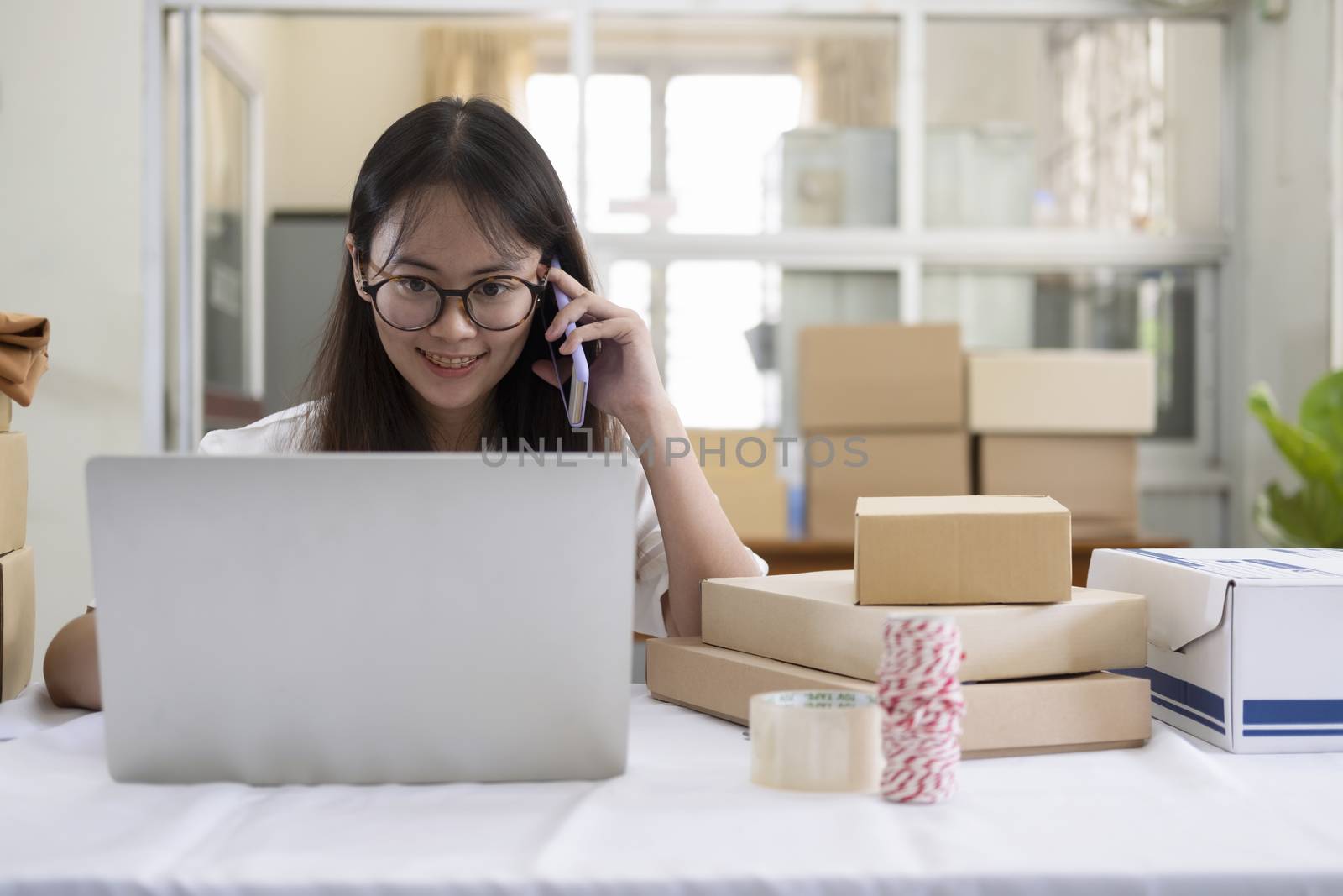 Selling online work from home. Young start up online selling store owner talking on phone to receive and checking order from customers. 