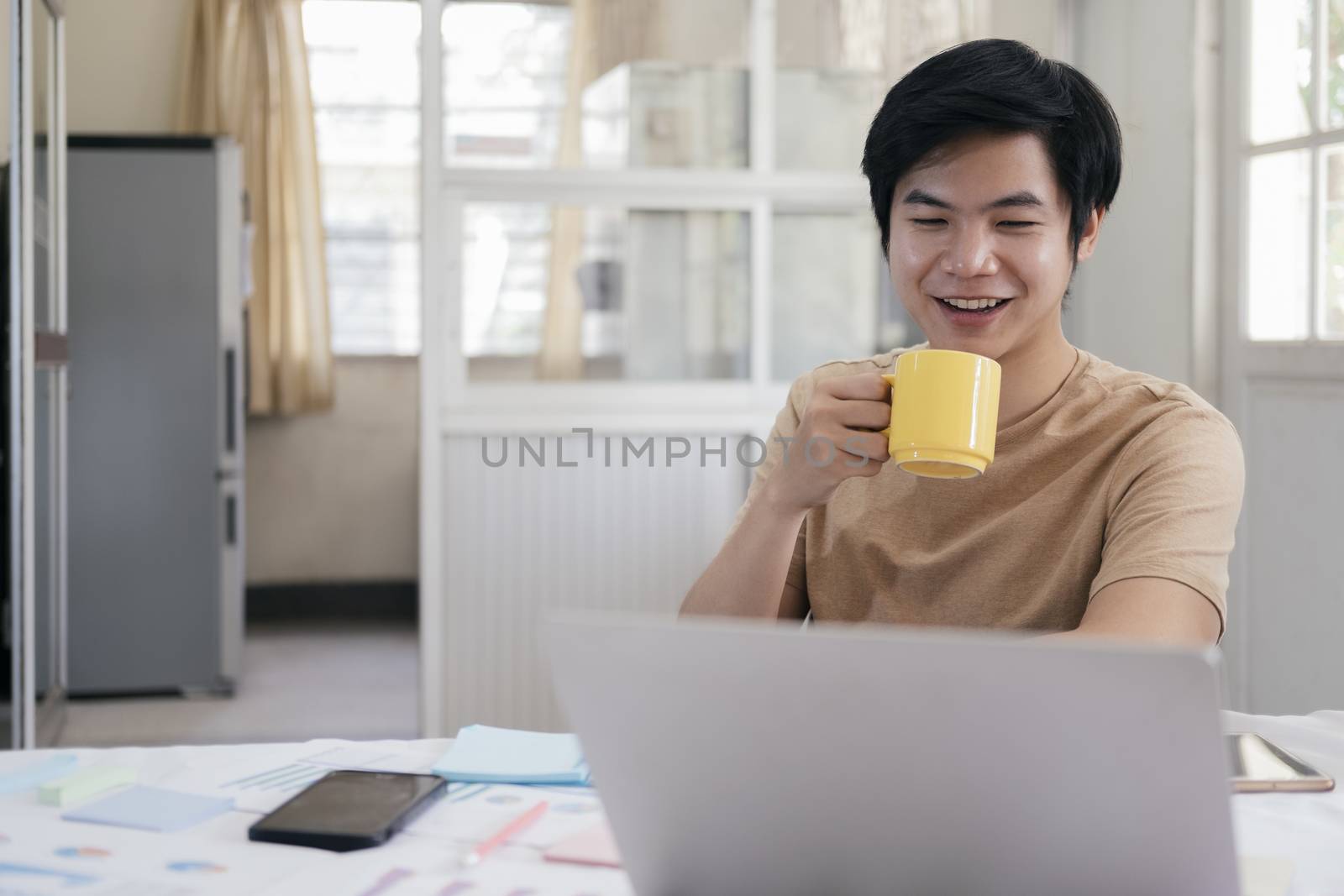 Young man relax with a cup of coffee and using computer laptop a by ijeab