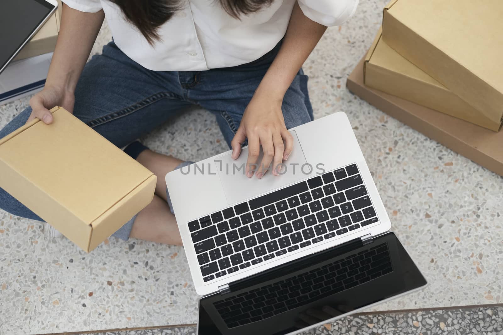 Young business start up online seller owner using computer for checking the customer orders from email or website and preparing packages for product office equipment.