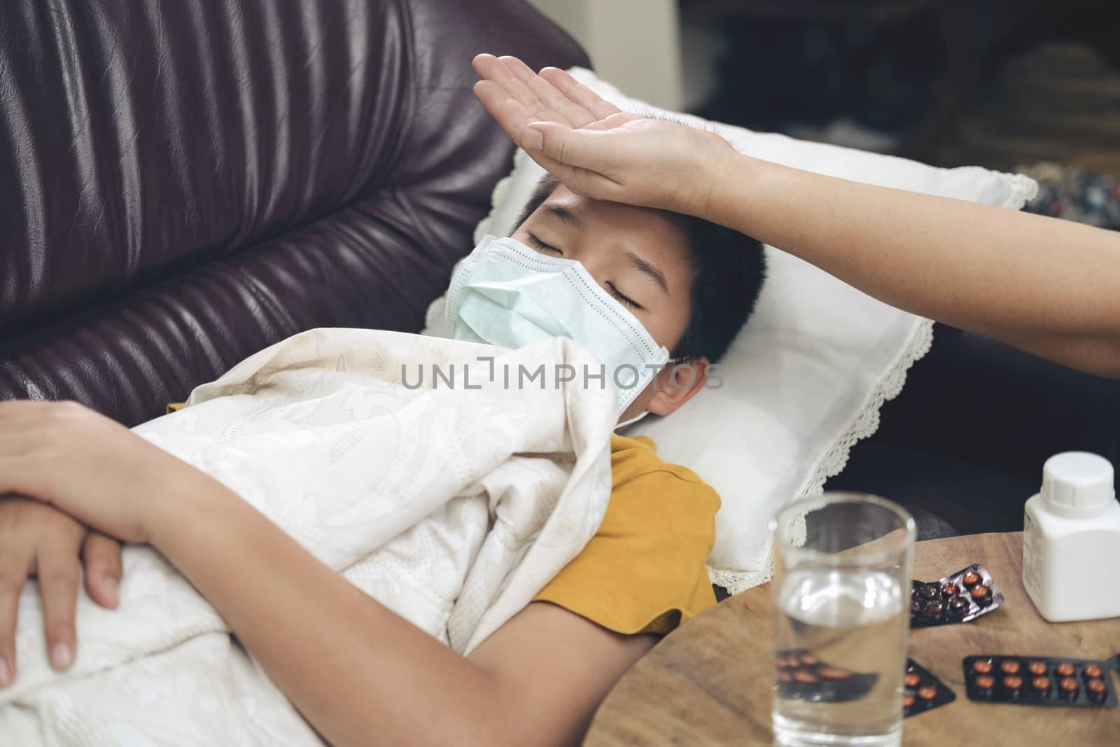 Sick child lying in sofa bed with protection mask on face against infection.