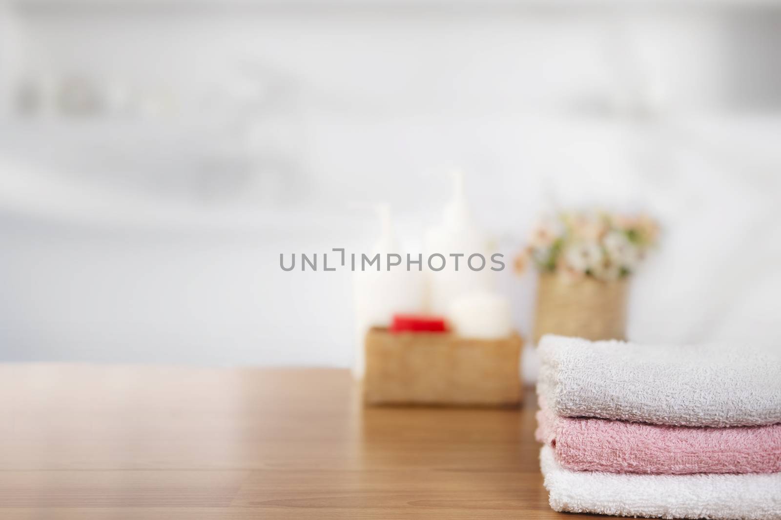 Towels on wooden top table with copy space on blurred bathroom background. For product display montage.