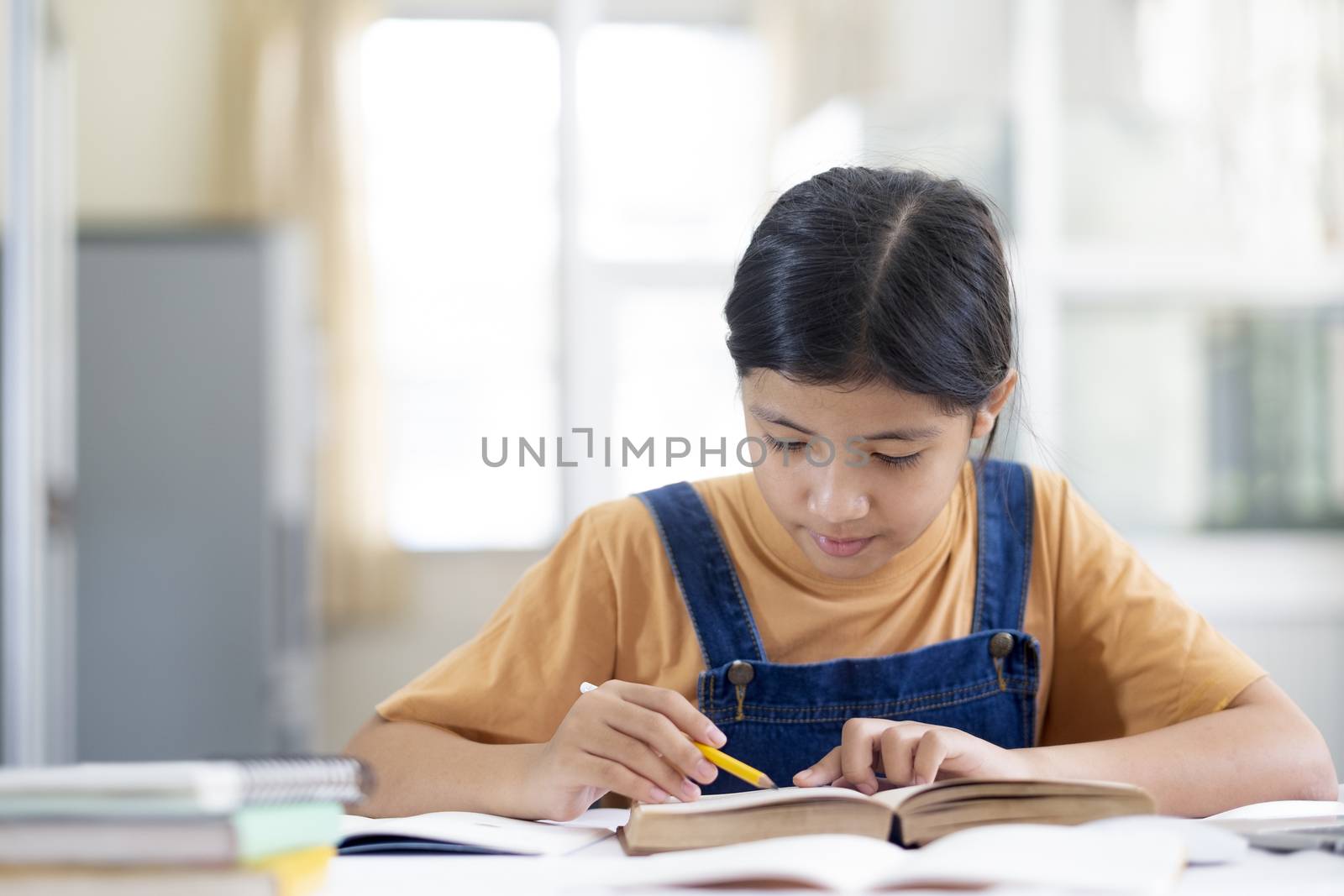 Asian girl reading and doing homework at her home. Education and self learning concept. 