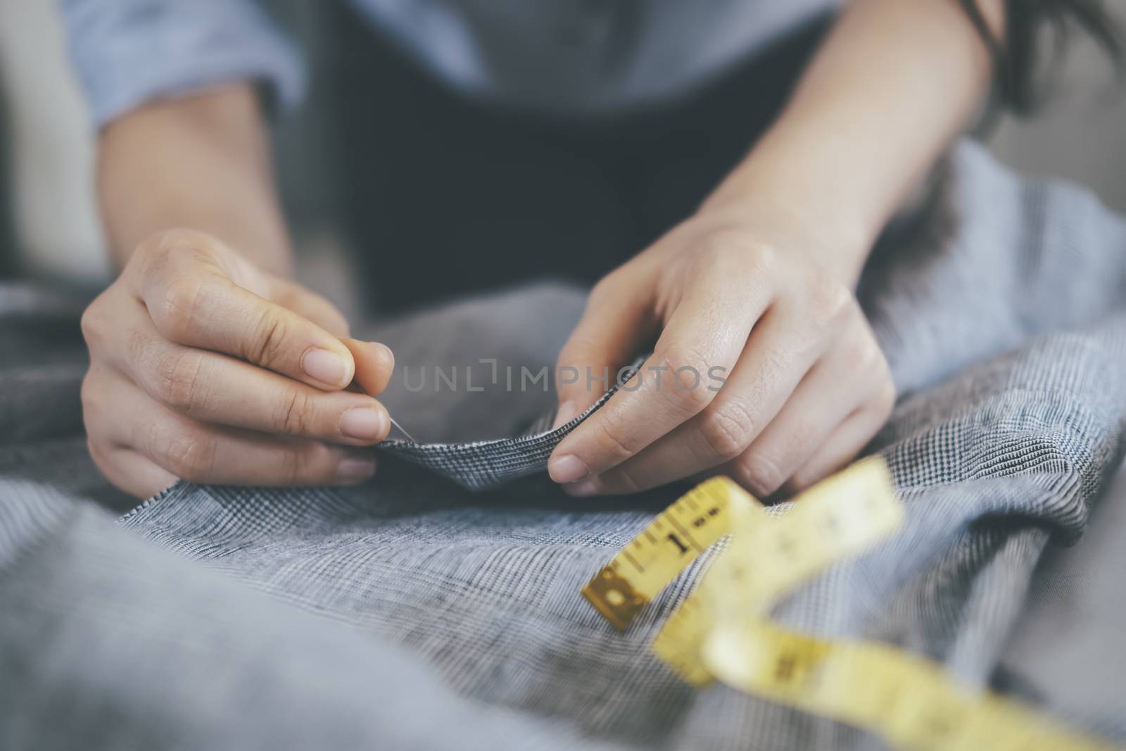 Closeup young woman tailor sawing jacket on on working table.
