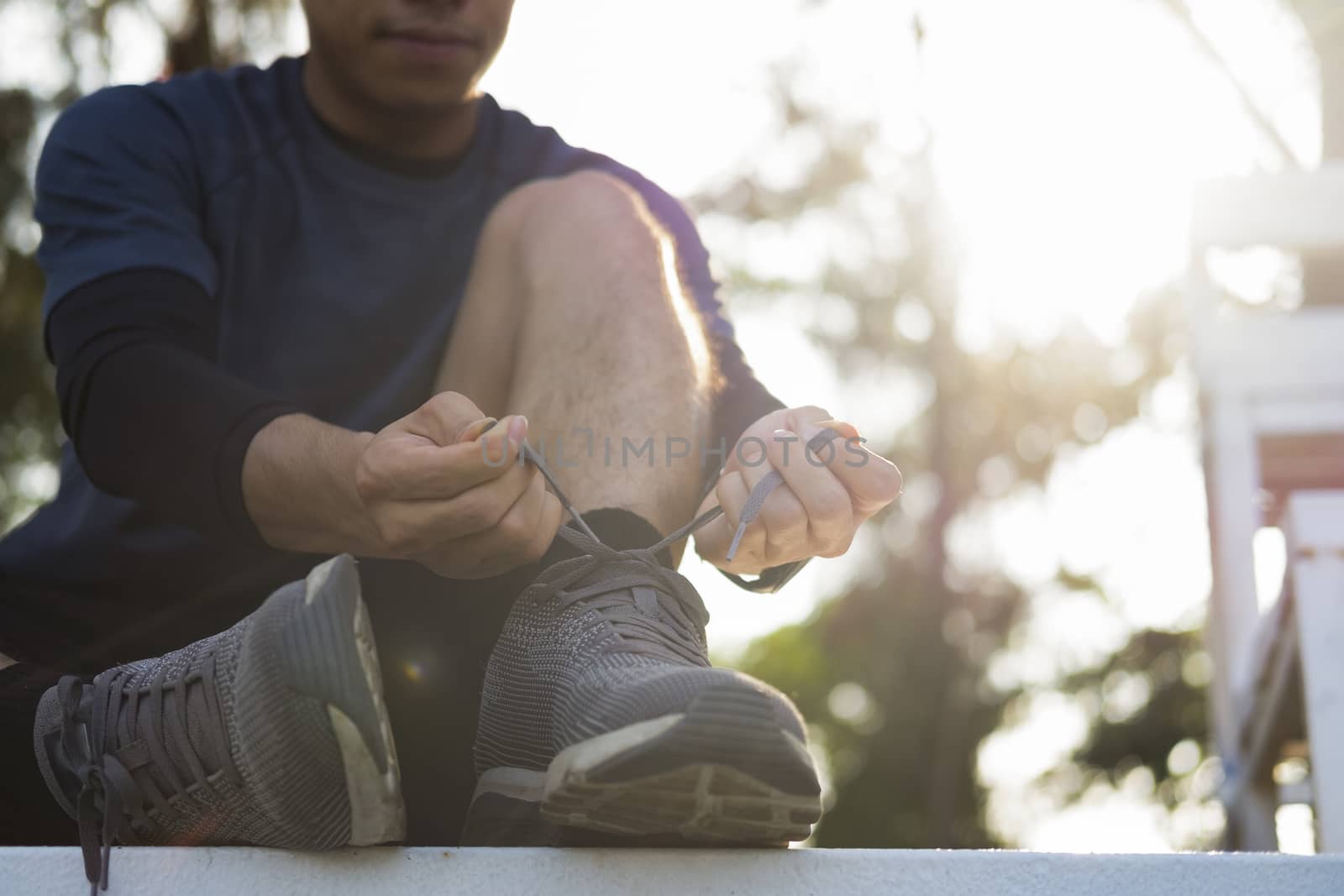 Sport and running idea concept. Young man runner tying shoelaces.