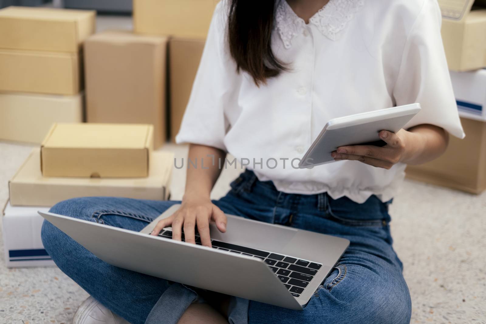 Young business start up online seller owner using computer for checking the customer orders from email or website and preparing packages for product office equipment.