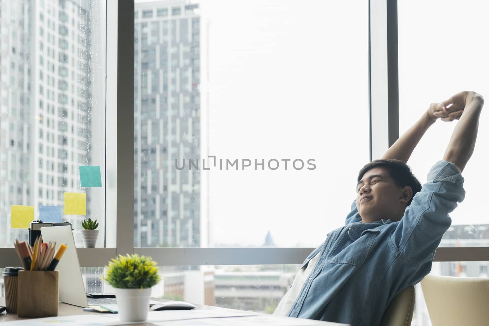 Young businessman is relaxing in office and  stretching his body by ijeab