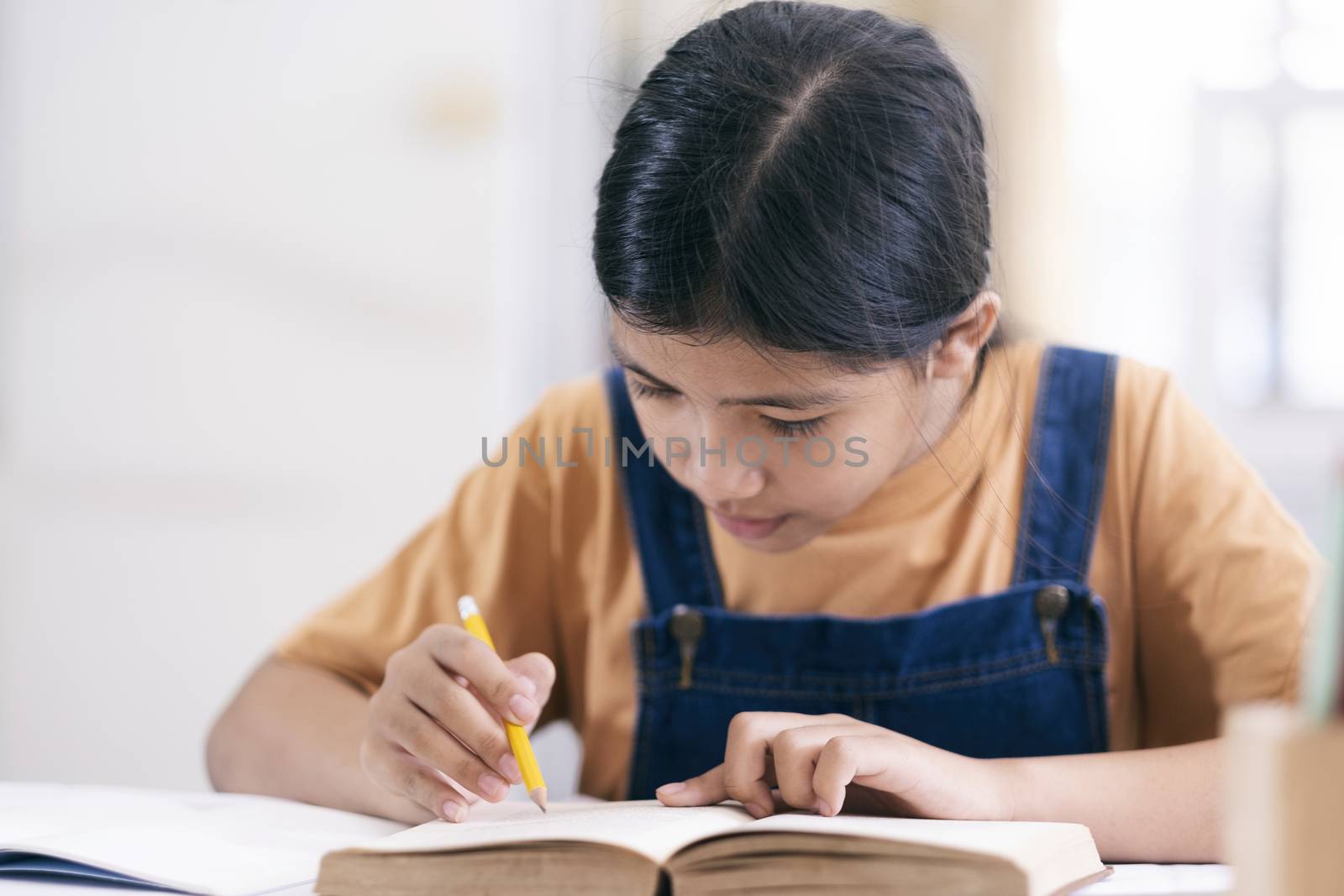 Asian girl reading and doing homework at her home by ijeab