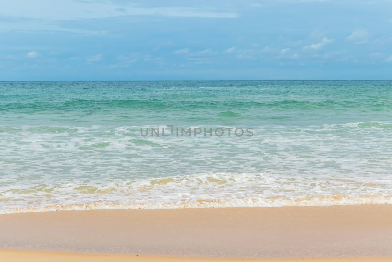 sandy beach blue sky and white formy wave