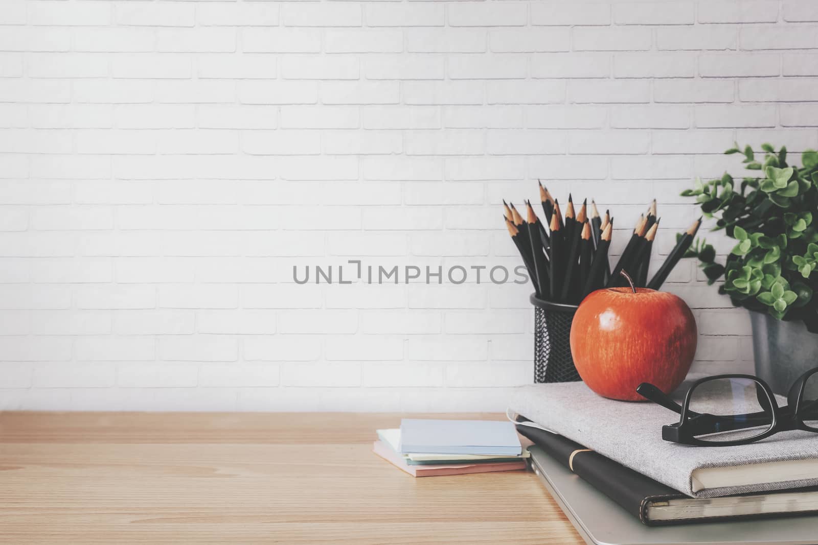 Copyspace of minimal workplace with office supplies on wooden table and white wall background.