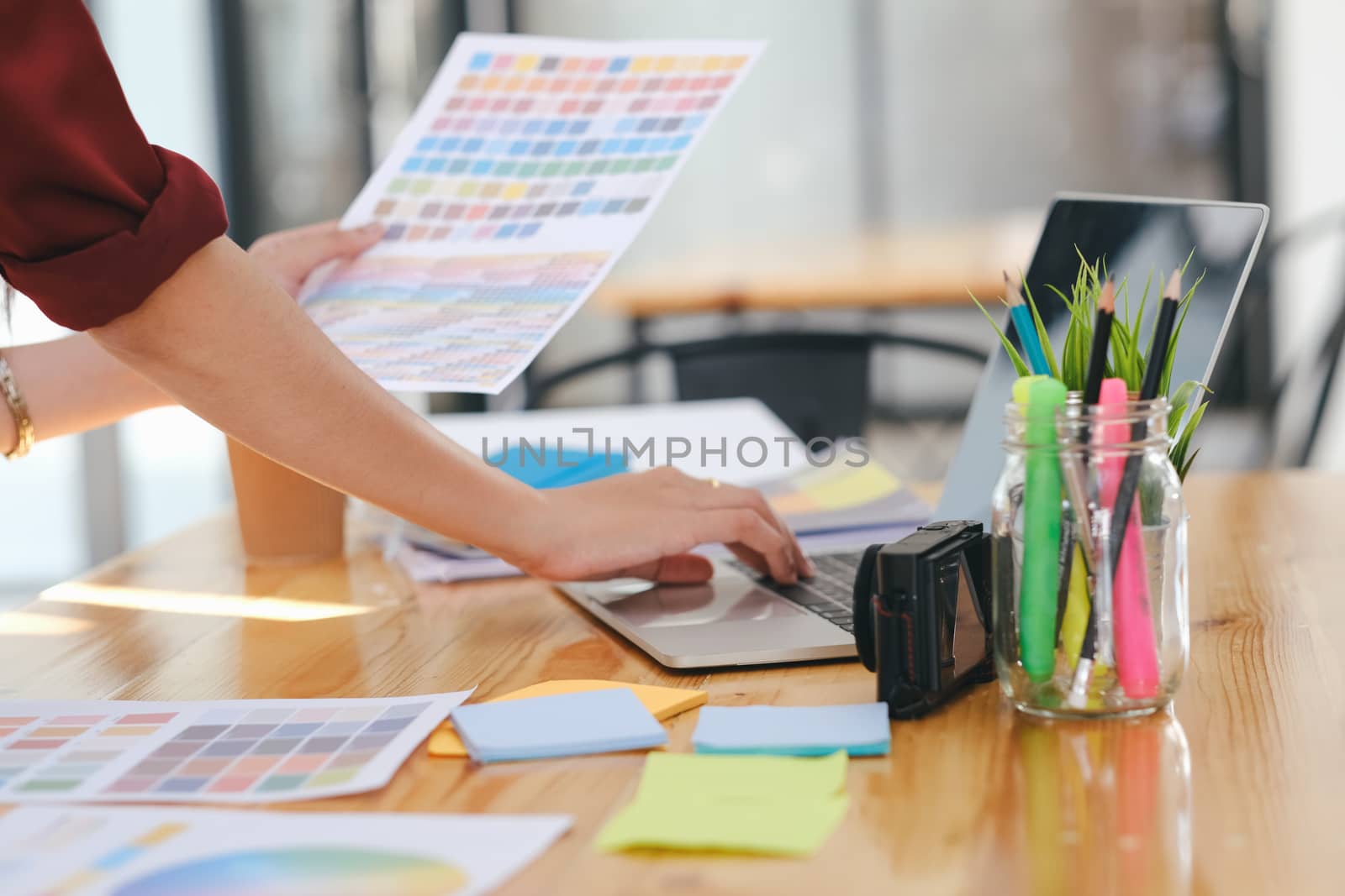 Graphic designer working with color samples for selection. Graphic designer at work. Color swatch samples. Young photographer and graphic designer at work in office.