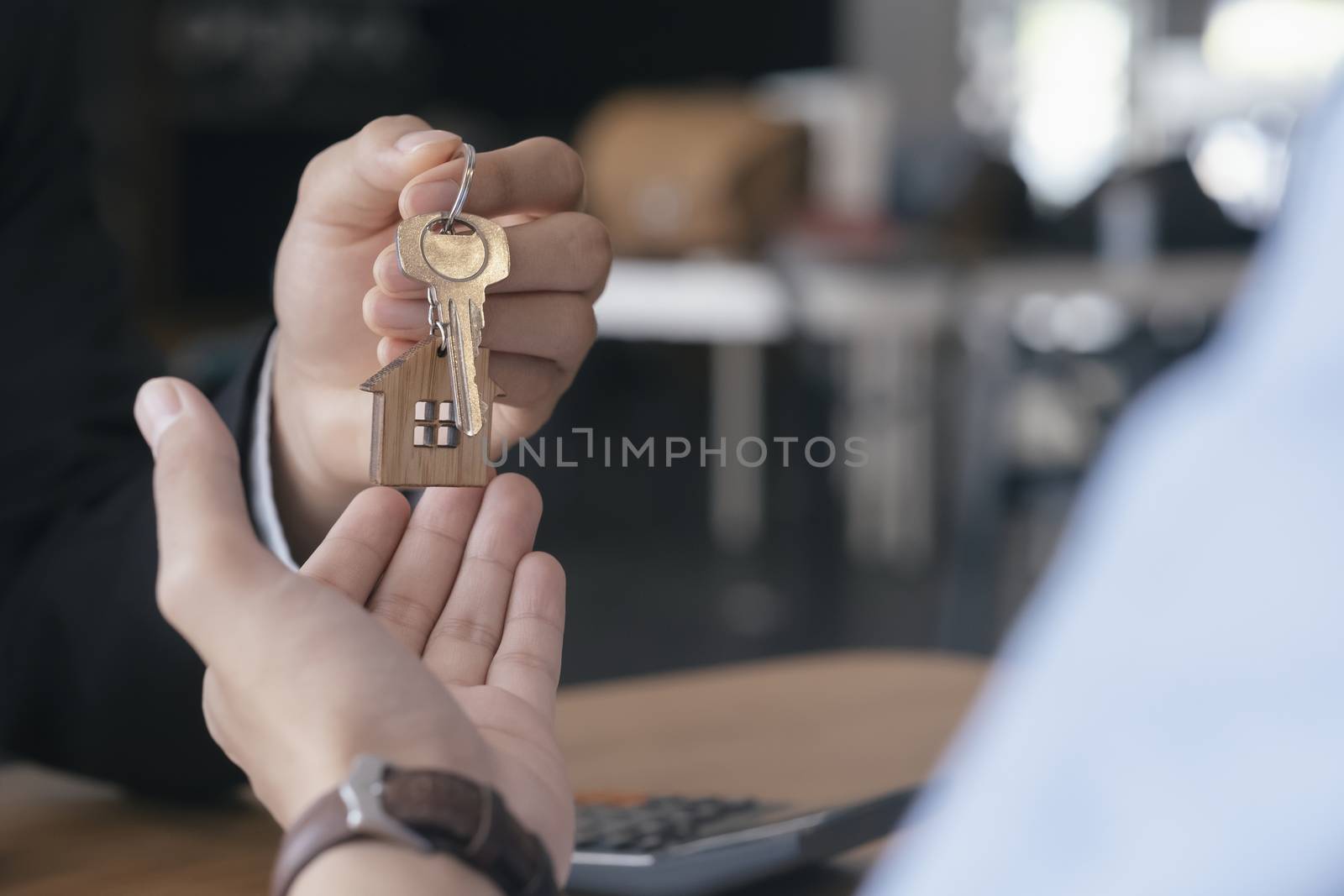 Close up view of young man taking keys from real estate agent during meeting after signing rental lease contract or sale purchase agreement. Young man purchasing new home. Real estate buy or rent or home insurance concept. 