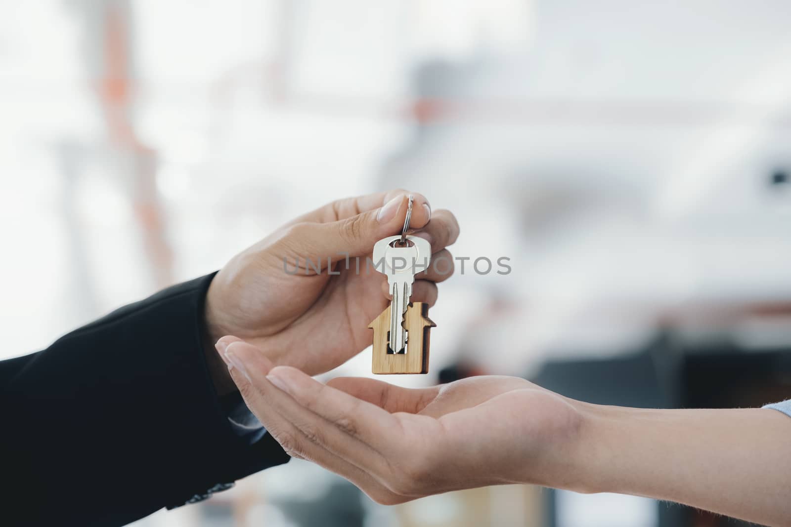 Real estate agent  holding key with house shaped keychain.  by ijeab