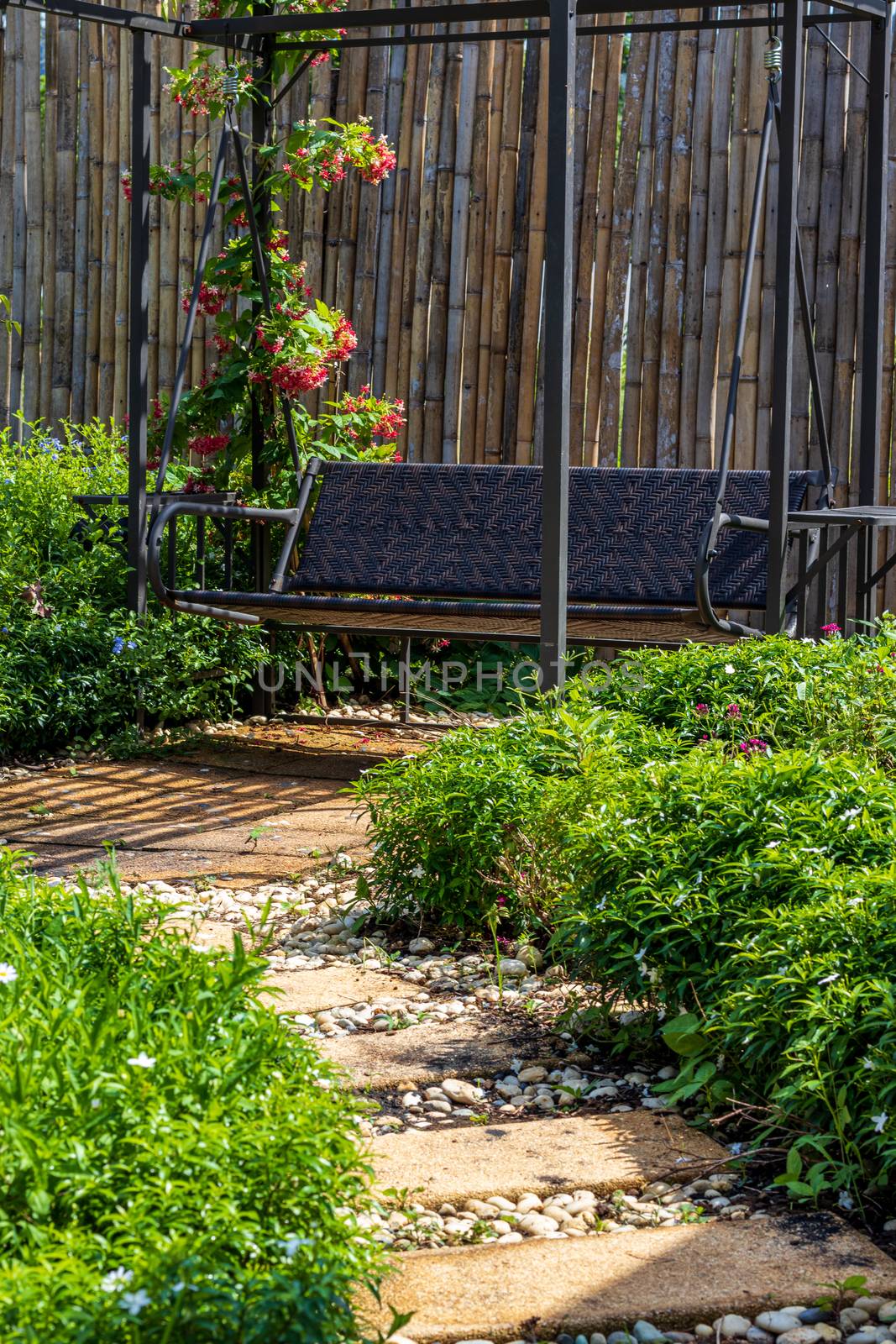 Art bench and flowers in the garden and footpath bettween green  by Khankeawsanan