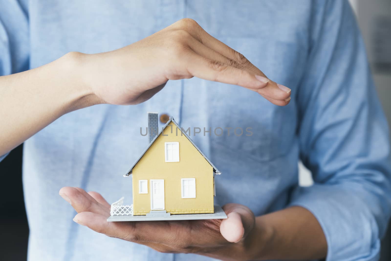 Businessman hand hold the house model saving small house. House insurance.
