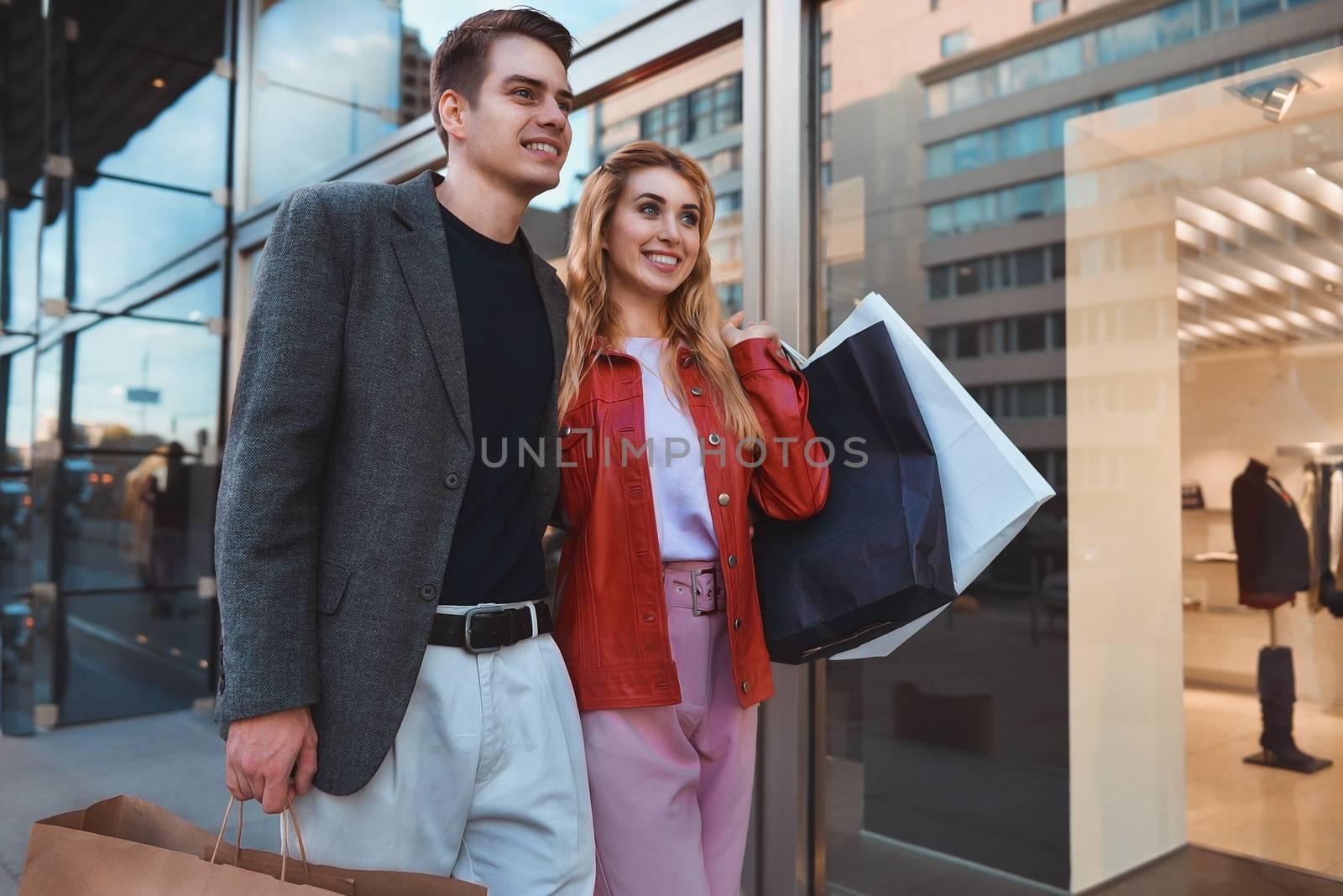 Beautiful young couple enjoying in shopping, having fun together. Consumerism, love, dating, lifestyle concept. by Nickstock
