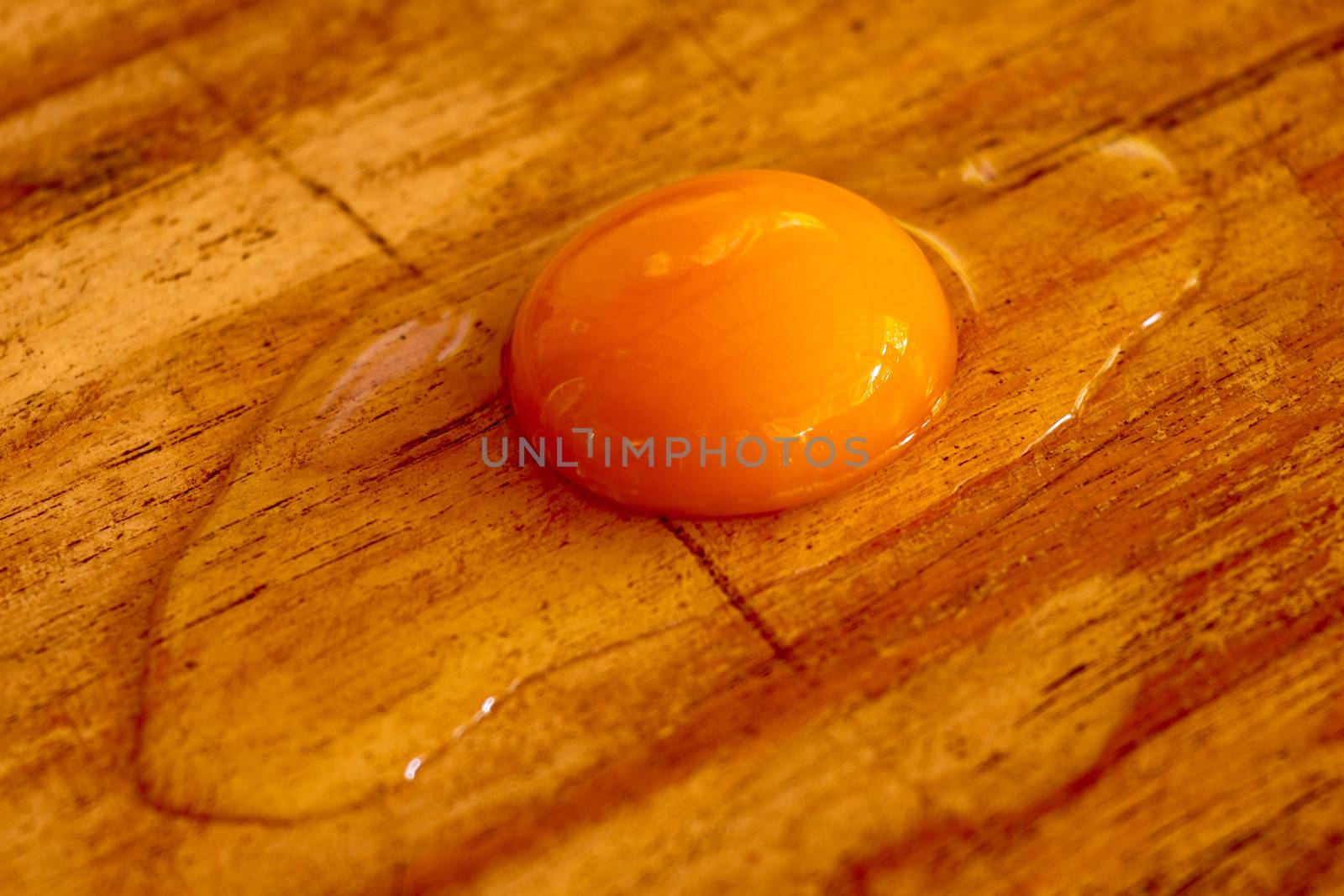 Broken raw egg on the chopping board. Broken egg on brown wooden table. Top view.