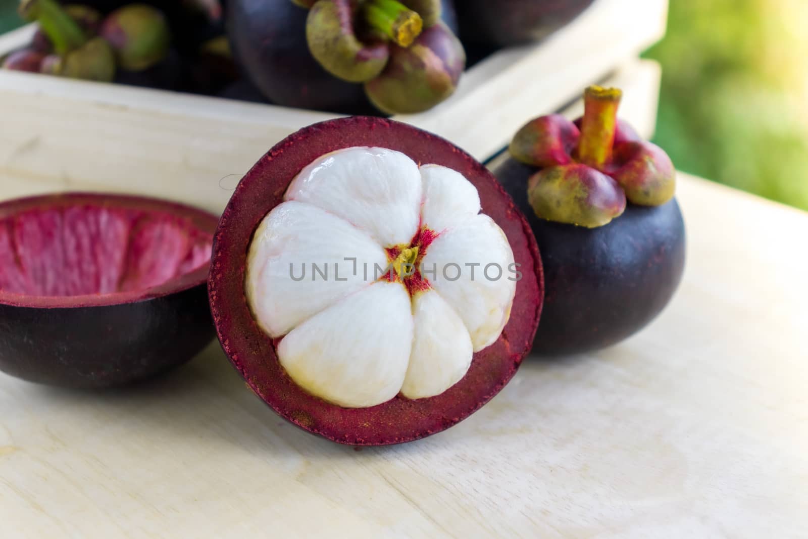 Mangosteen - The Queen of Tropical Fruit, dark-purple skin and creamy white fruit flash on wooden table