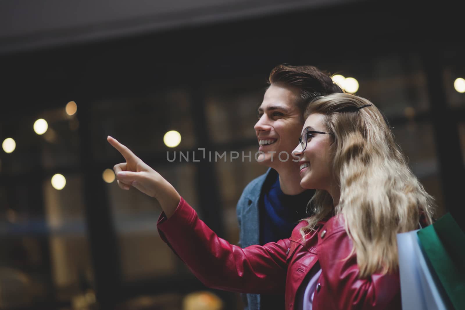 Beautiful young couple enjoying in shopping, having fun together. Consumerism, love, dating, lifestyle concept. by Nickstock