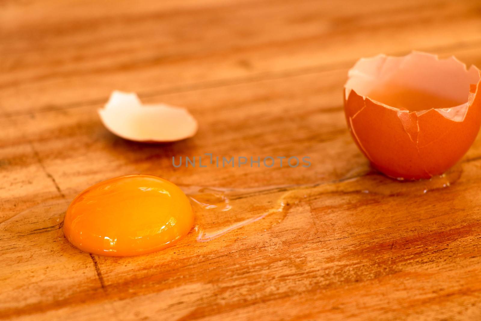 Raw broken colour egg with yellow yolk.Chicken raw, farm eggs on old wooden table.