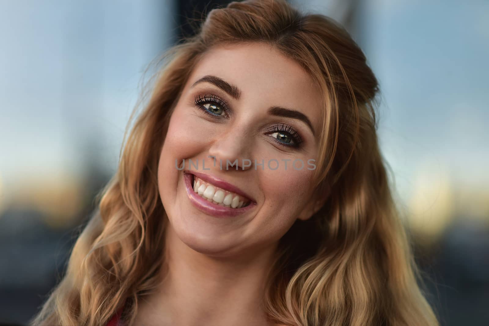 Close up portrait of a beautiful smiling girl with nice teeth outdoors at street. by Nickstock