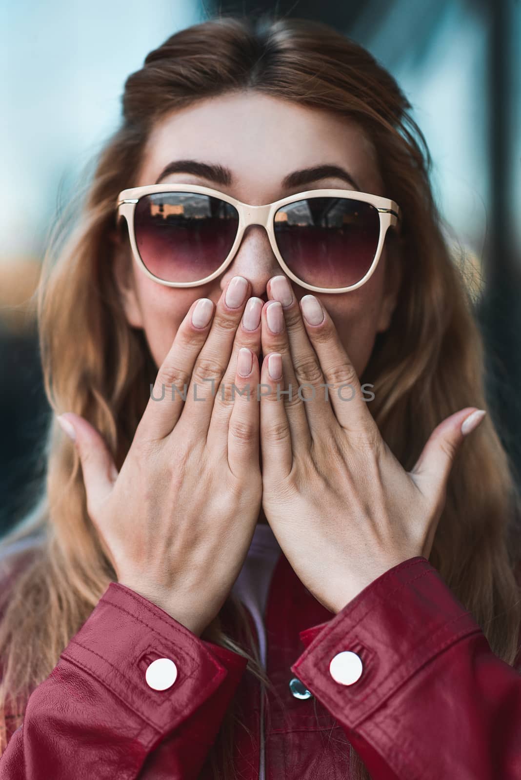 Closeup portrait of beautiful pensive blonde white Caucasian girl woman, weared in red jacket outside in city street, lifestyle portrait concept