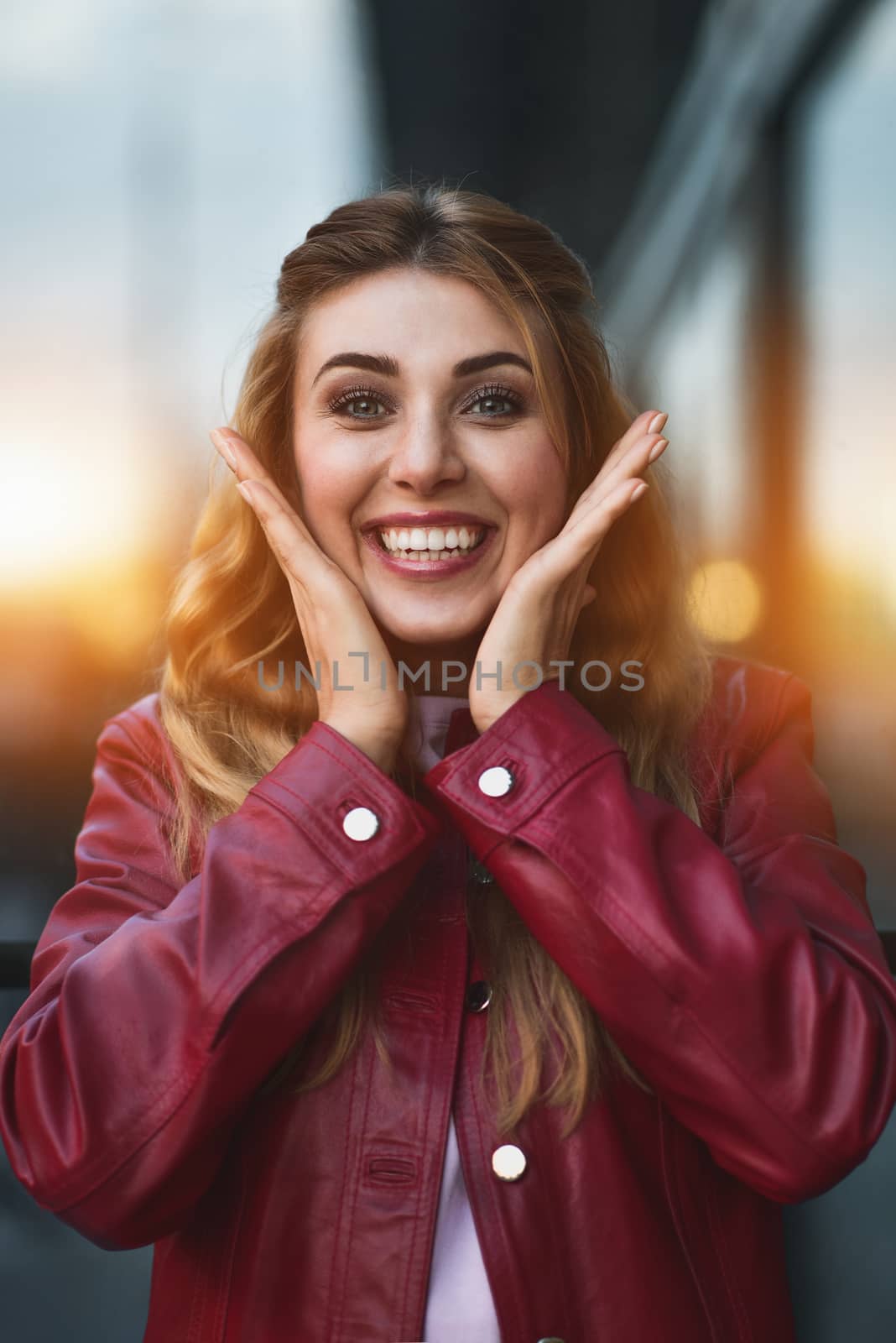 Closeup portrait of beautiful pensive blonde white Caucasian girl woman, weared in red jacket outside in city street, lifestyle portrait concept
