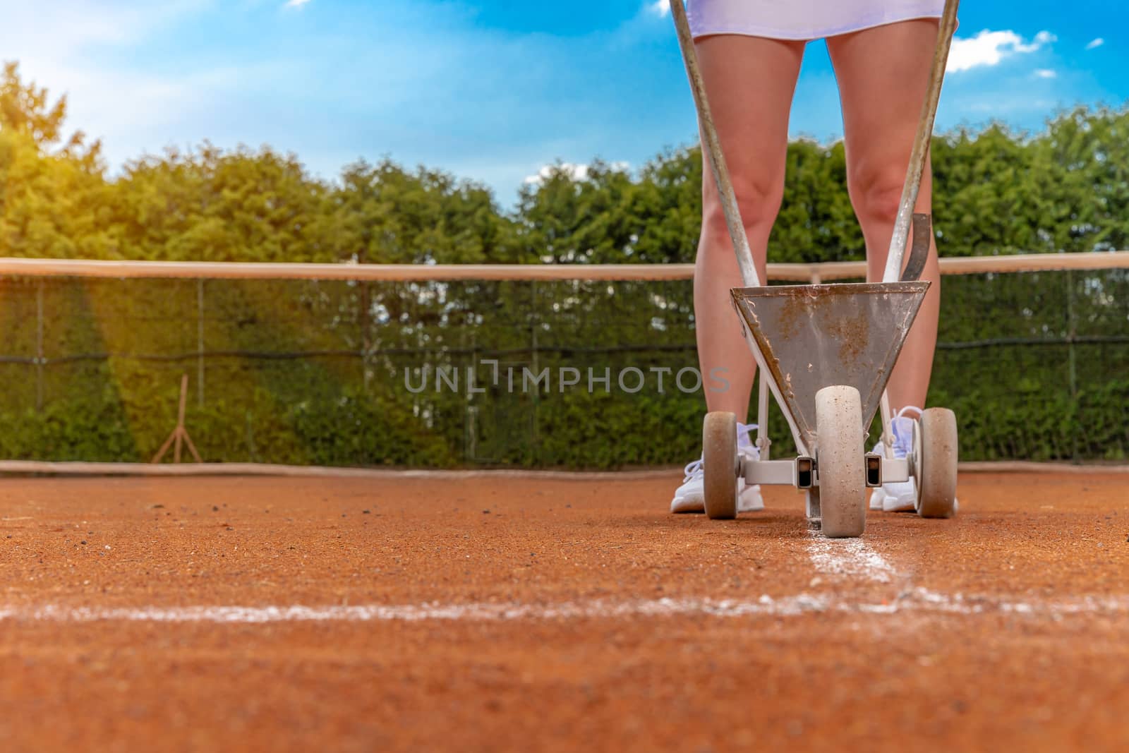 drawing white lines with lime. maintenance and repair of tennis courts. copy space by Edophoto