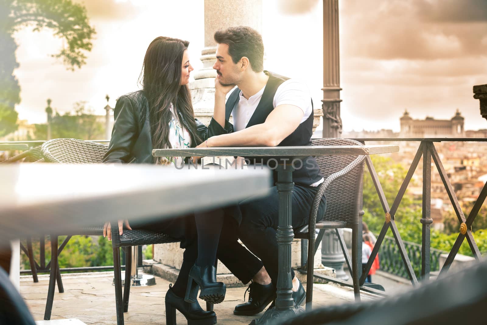 Pair of lovers seated at the restaurant. Couple in love. On vacation in Rome, Italy. Monuments in the distance.