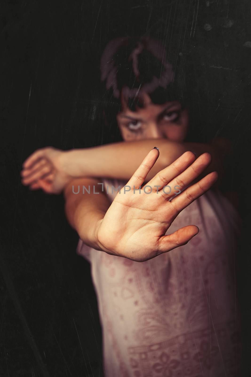 Refusing, violence against women. A young girl with her hand away and rejects violence of someone. Tears and crying. Black background. Focus on the hand.