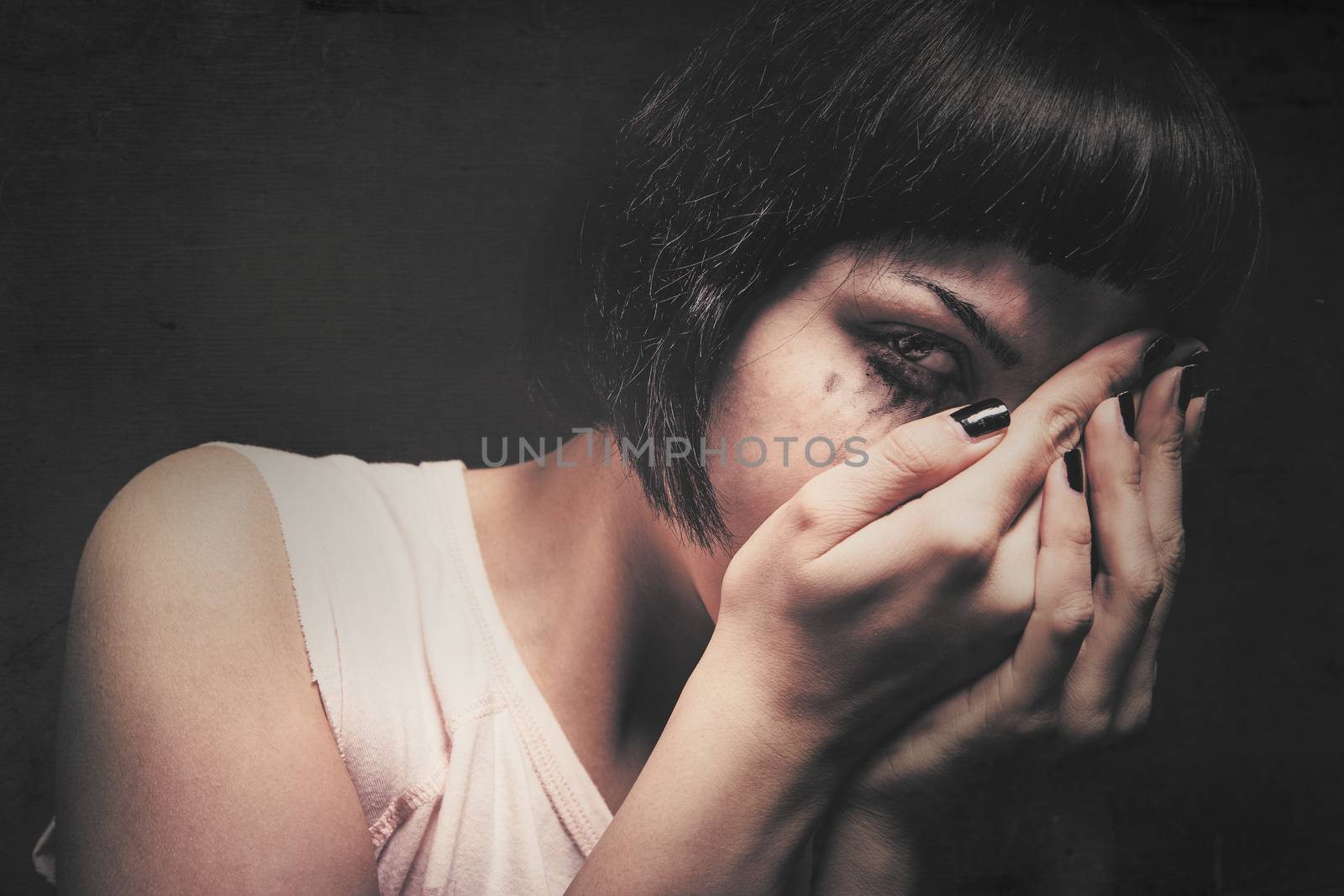 Young woman crying with her hands in her face. Domestic violence. Drained makeup.