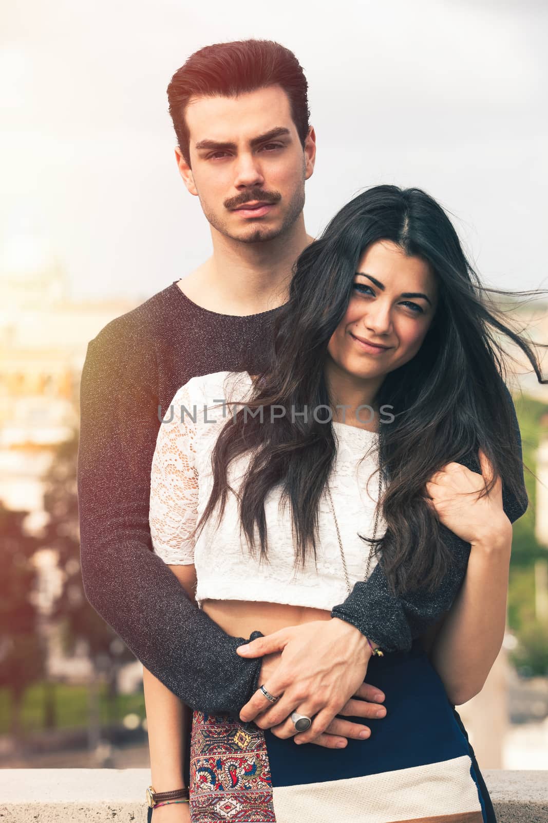 Holiday in Rome. Beautiful lovely young italian couple embracing outdoors. A couple, young man and a woman outdoors, is embracing on a terrace in the historic center of Rome, Italy.