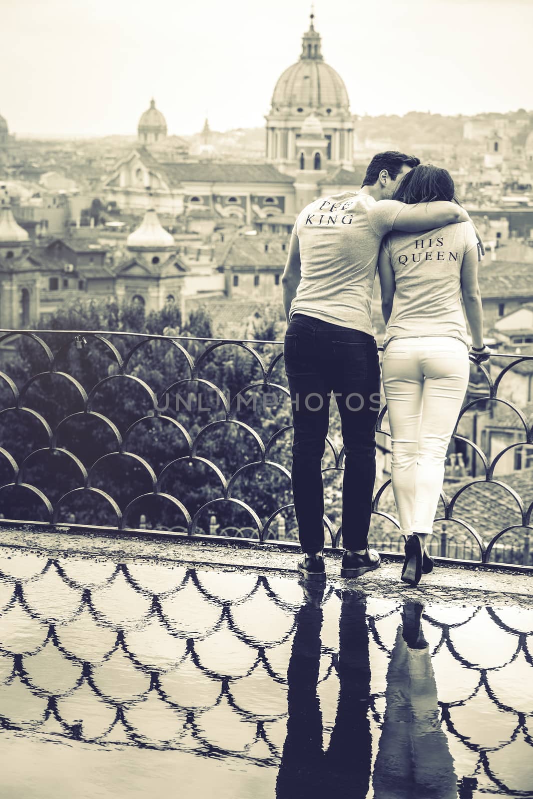 Couple hugging on holiday in Rome, Italy. Reflection in puddle. by angelocordeschi