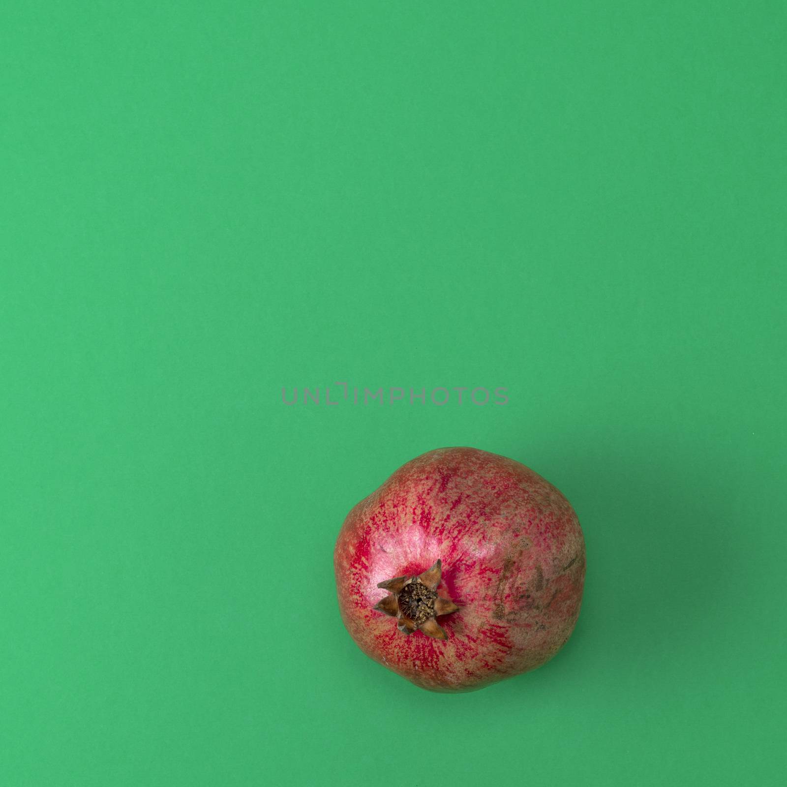 red pomegranate in the peel on a green background by ndanko