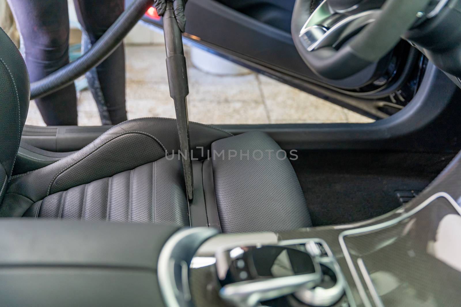 vacuuming the interior of a luxury car in the garage.