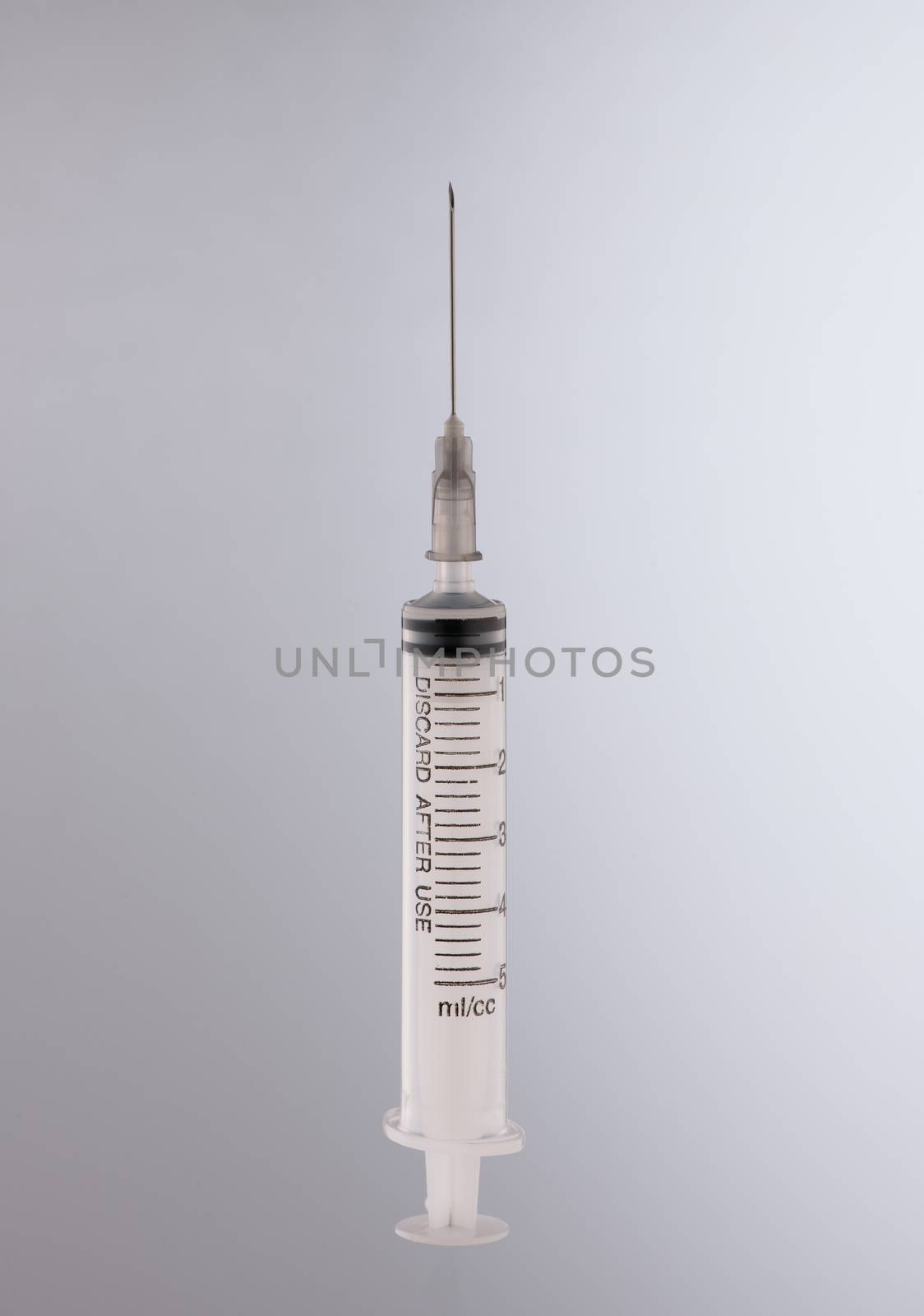 one medical syringe in an upright position on a light background