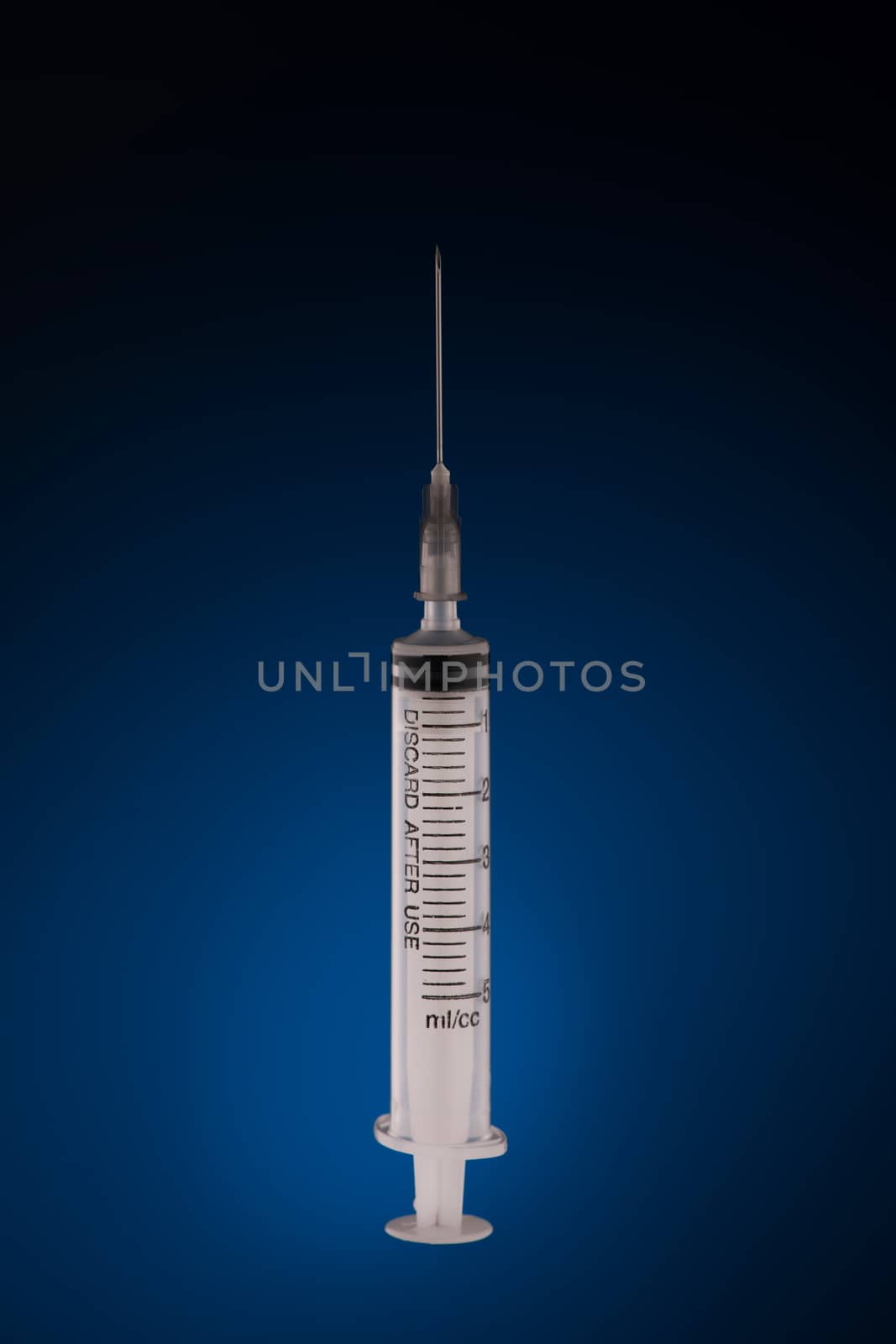 one medical syringe in an upright position on a dark blue background