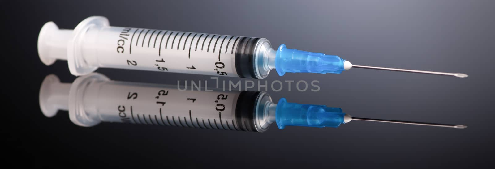 one medical syringe on a dark gray background with reflection