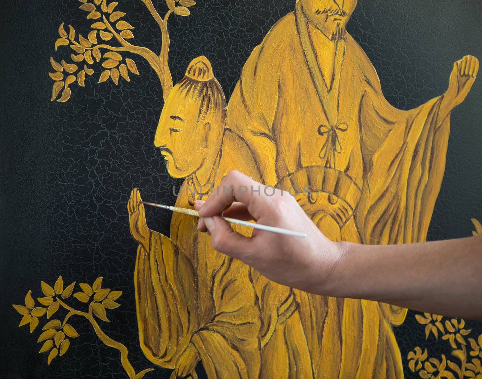 painter decorator draws Chinese pattern of leaves and man, macro shooting